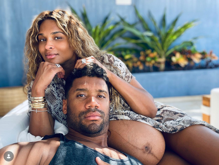 Ciara and Russell Wilson pose on a couch as Ciara shows her pregnant belly on June 27, 2020 | Source: Instagram/ciara