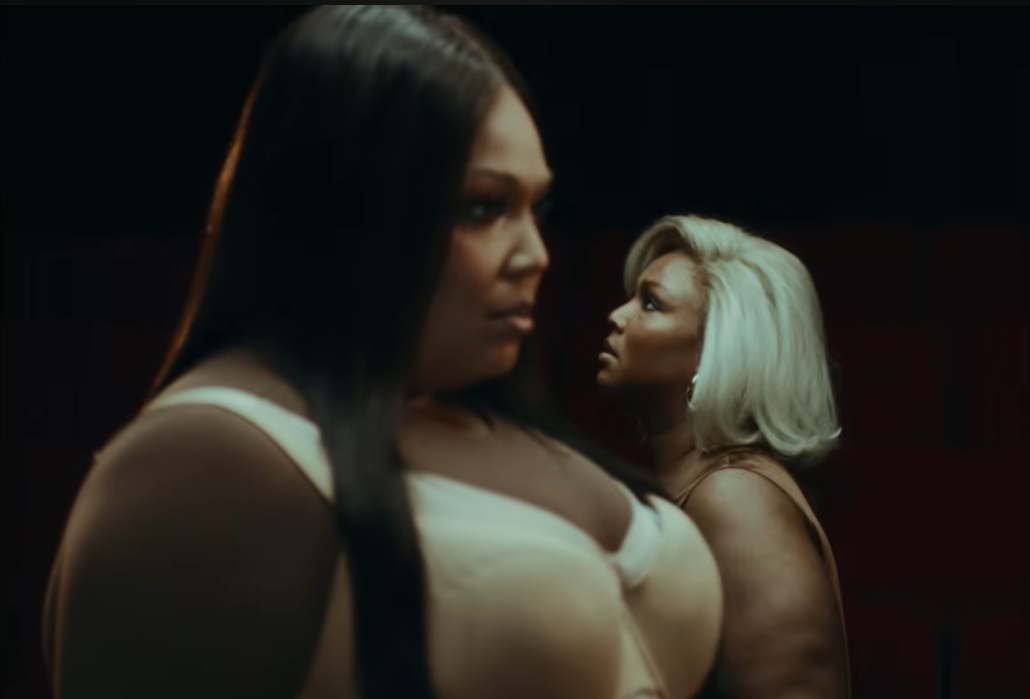 Lizzo and her alter ego stand side by side, their profiles aligned but distant | Source: YouTube/Lizzo