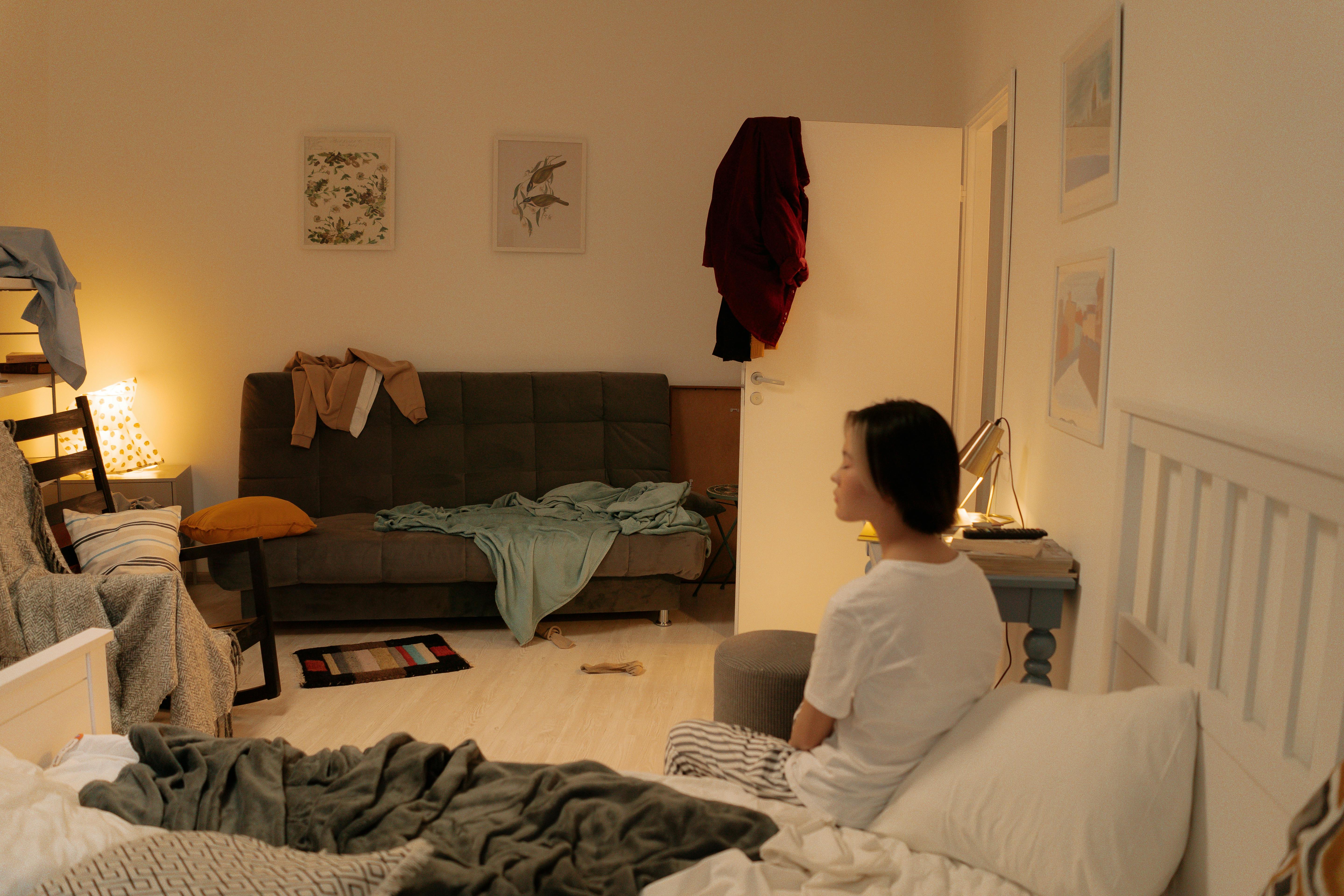 A messy bedroom with a woman sitting on the bed | Source: Pexels
