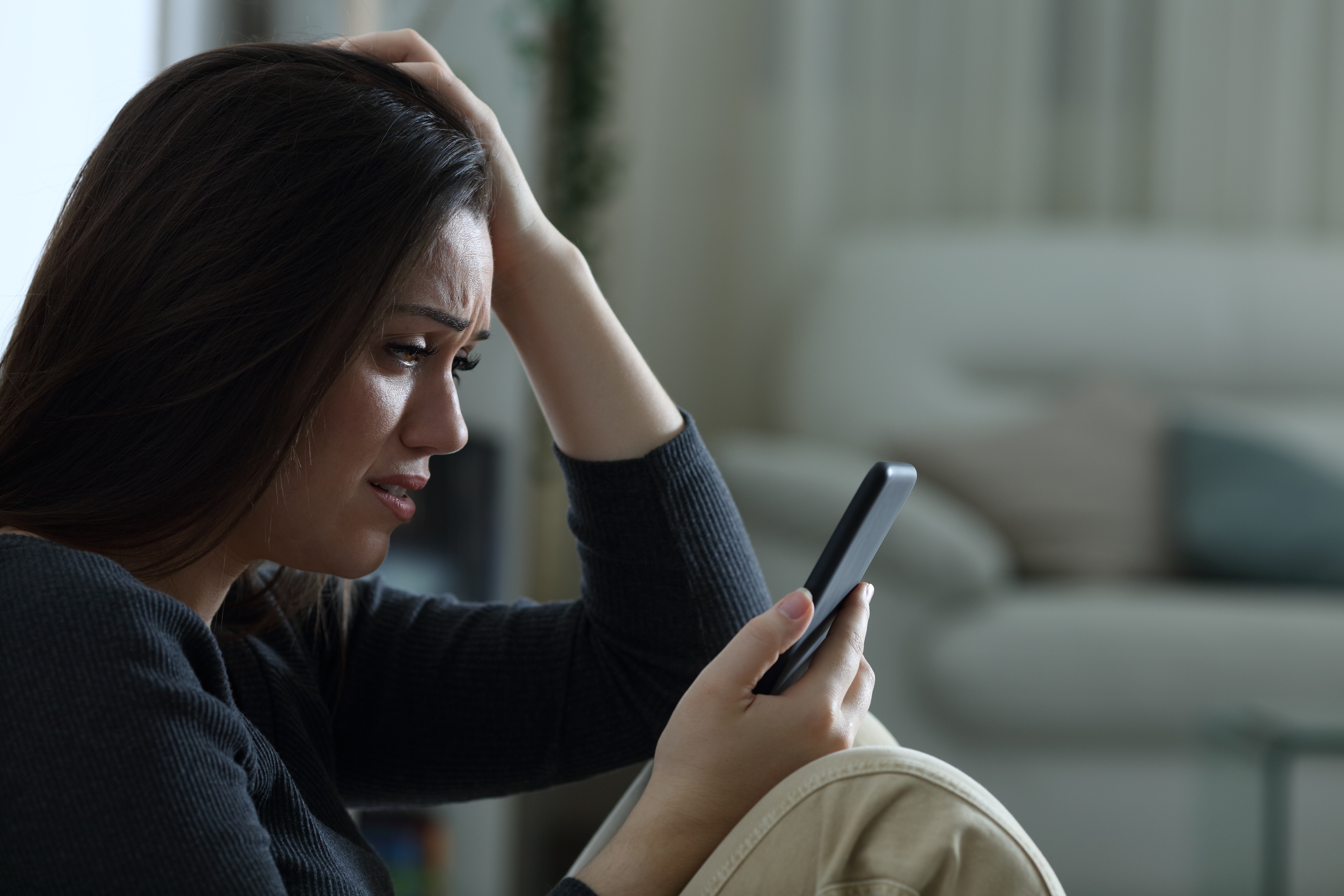 A woman looking sad while on her phone | Source: Shuttertsock