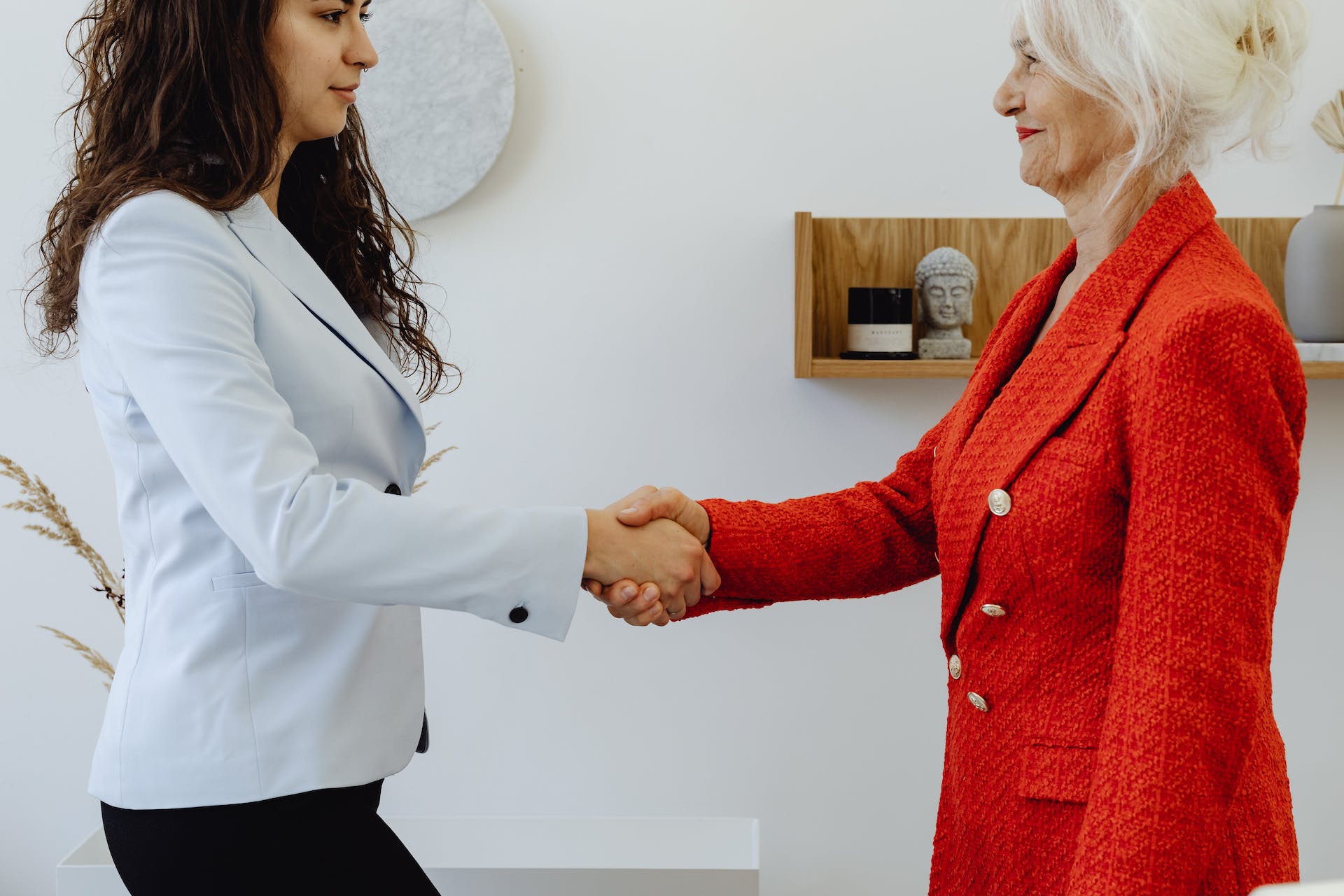Two women shaking hands in a formal setting | Source: Pexels