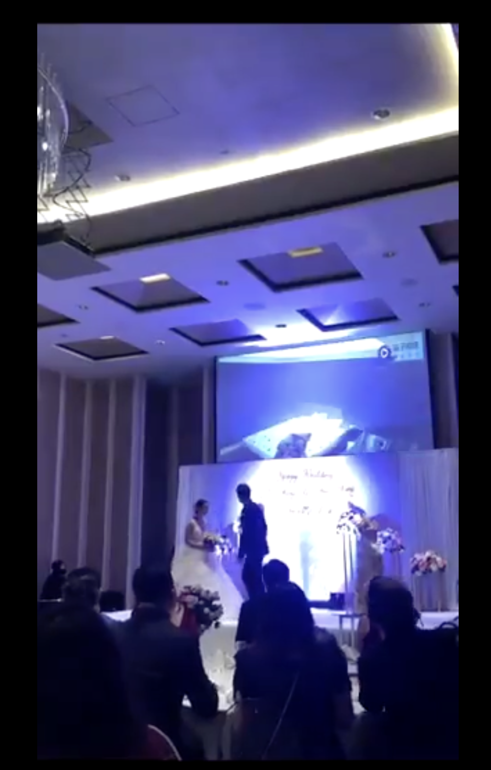 Die Braut und der Bräutigam wenden sich dem Projektor hinter ihnen zu | Quelle: twitter.com/TuanConCom1