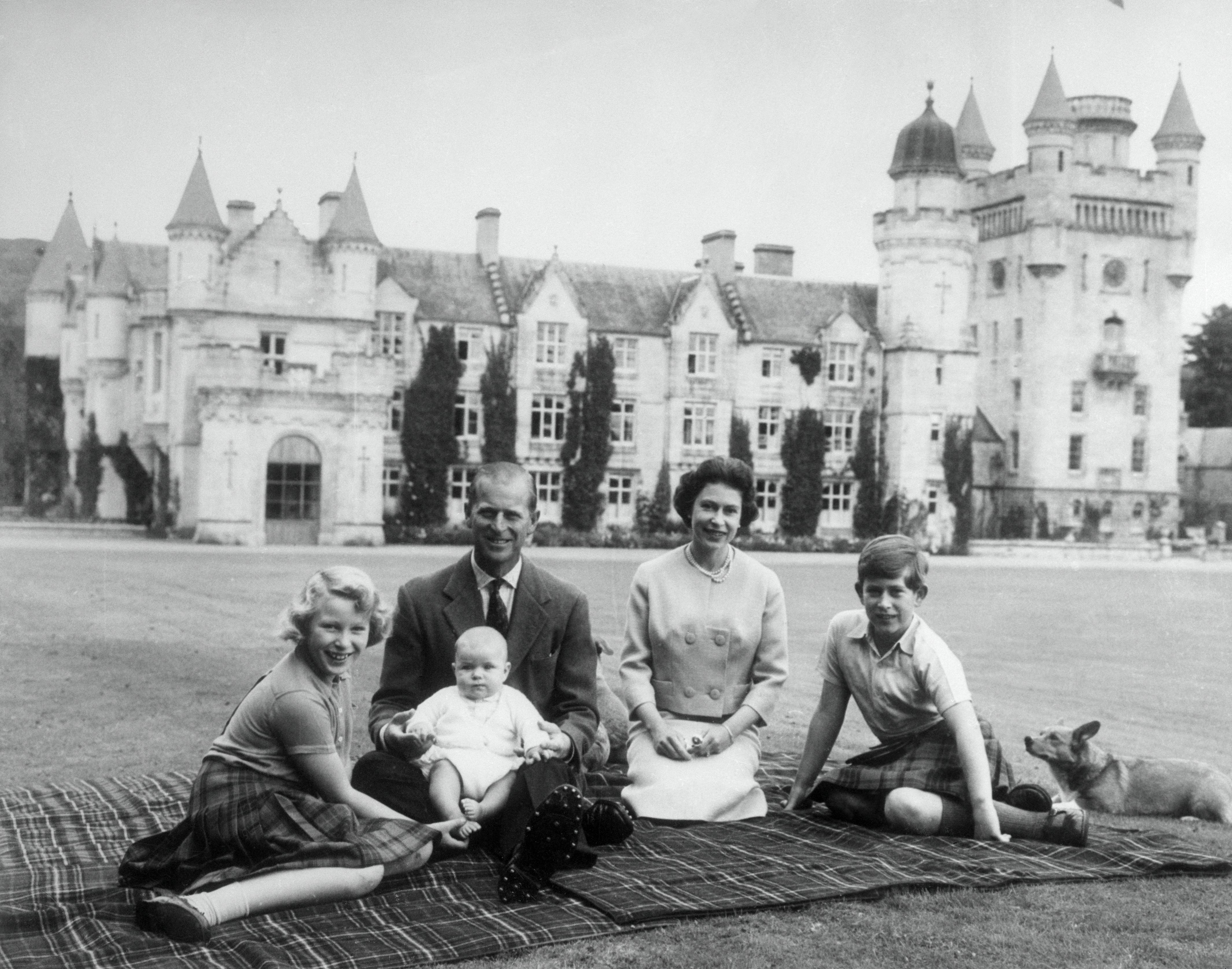 Königin Elizabeth II. und Prinz Philip sitzen mit ihren Kindern Prinz Andrew (Mitte), Prinzessin Anne (links) und Charles auf einer Picknickdecke vor Balmoral Castle in Schottland, 8. September 1960. | Quelle: Getty Images