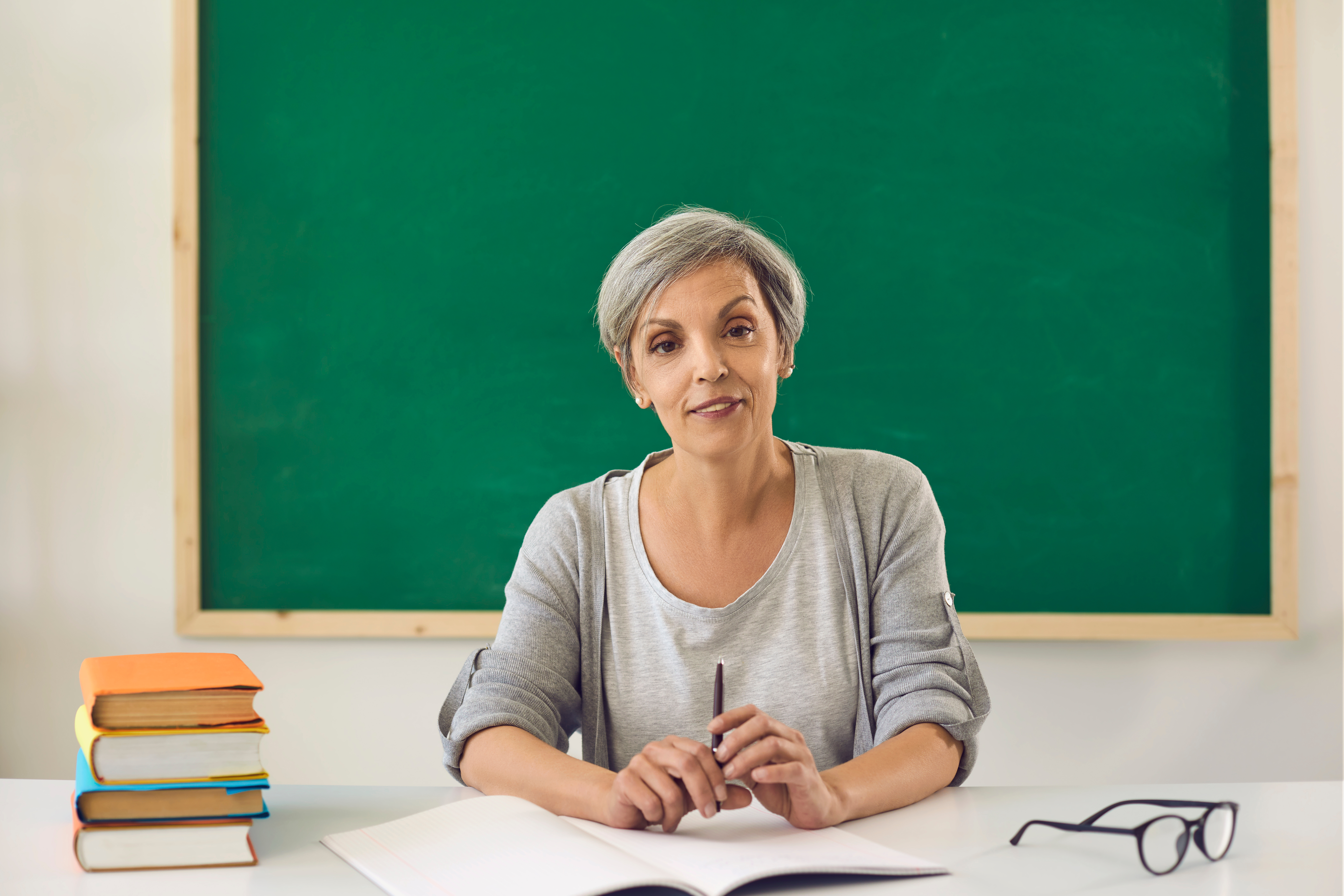 Teacher smiling from her desk | Source: Shutterstock