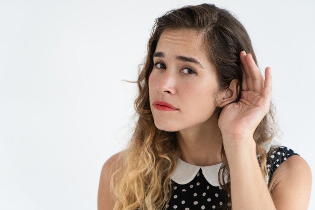 Konzentrierte hübsche junge Frau, die Hand nahe Ohr hält und Kamera betrachtet | Quelle: Shutterstock