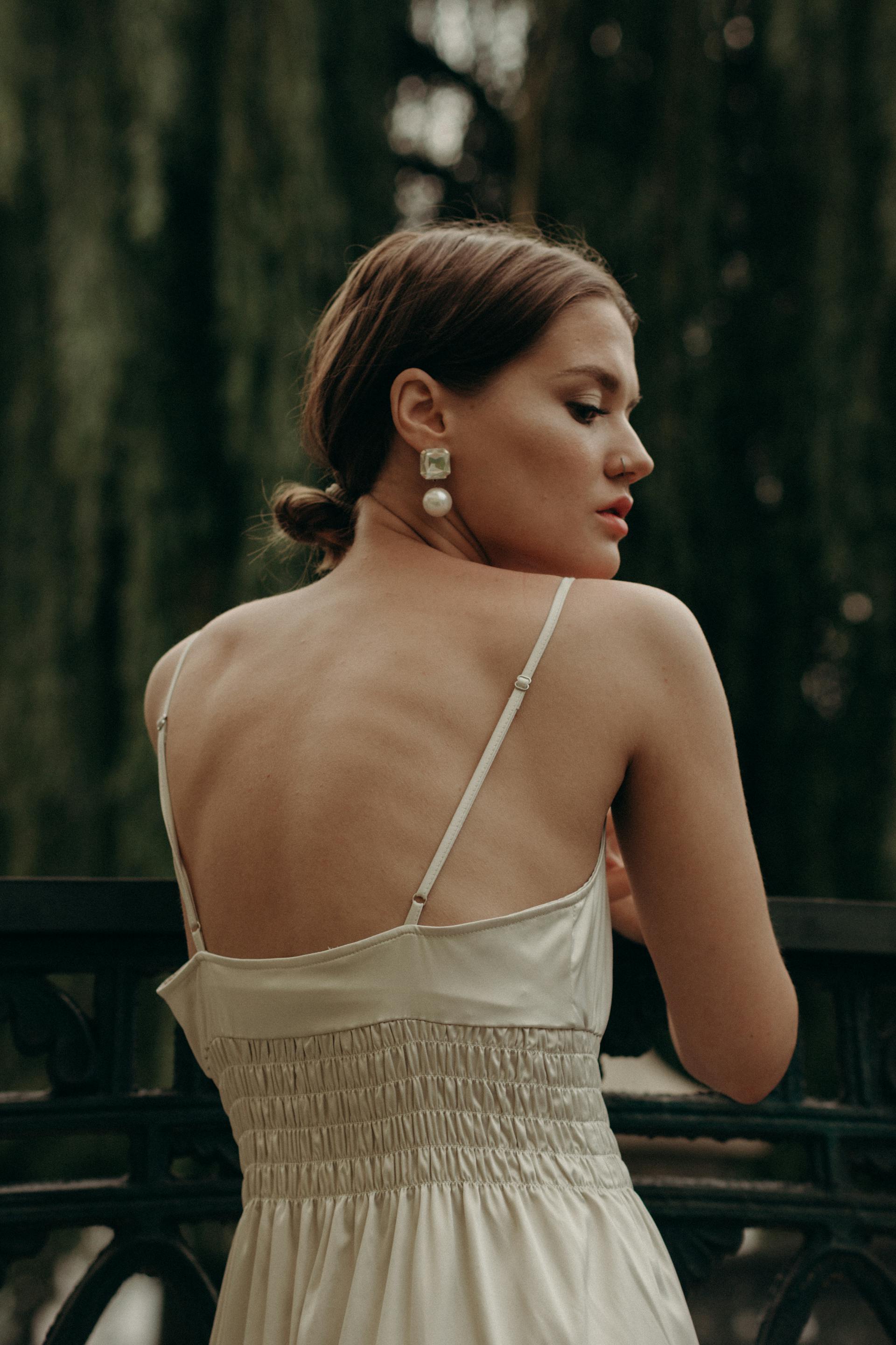 A woman in a white dress wearing matching earrings | Source: Pexels