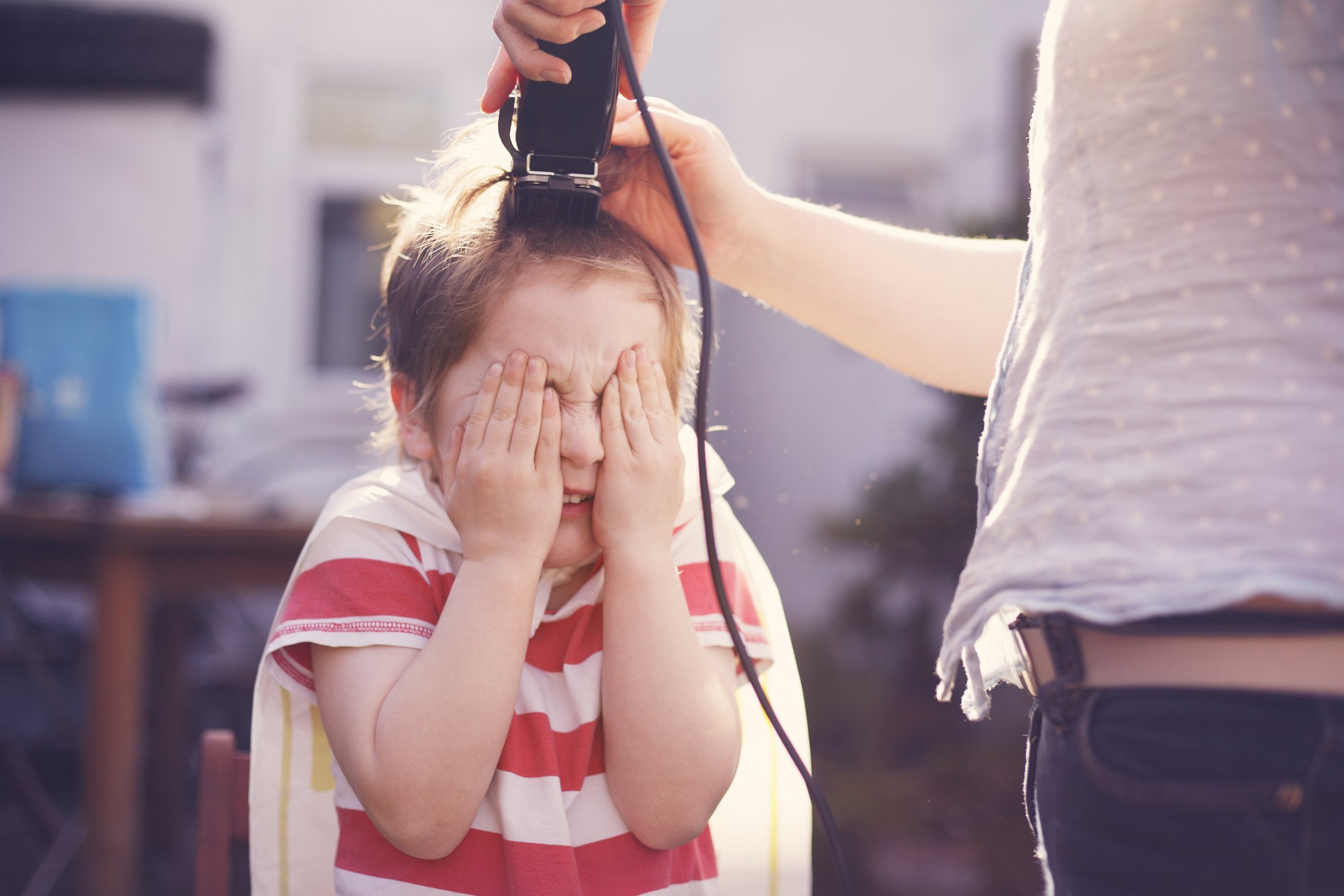 A young boy having his hair cut by his mother using hair clippers | Photo: Getty Images