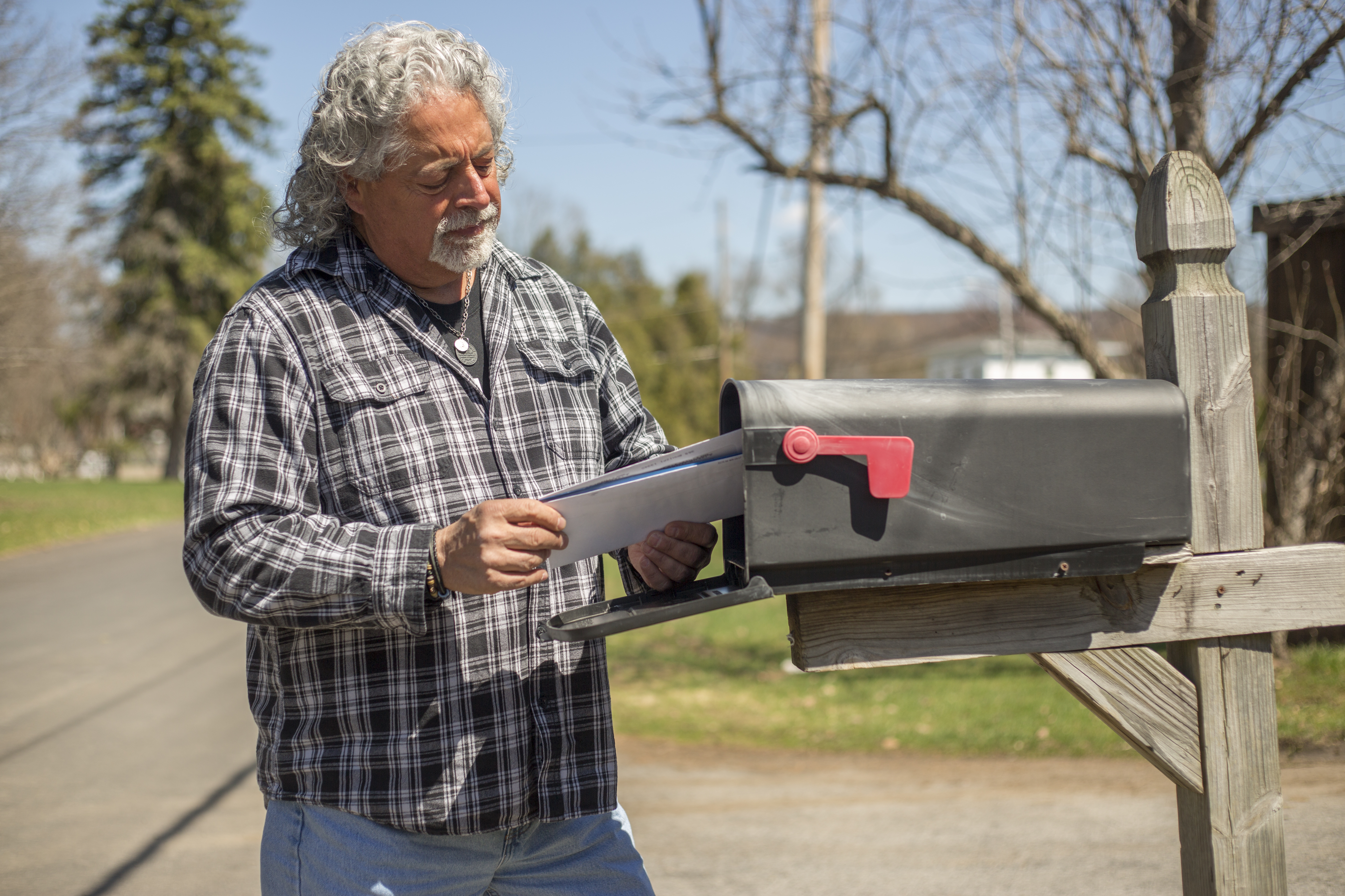 A man puts an envelope in a mailbox | Source: Shutterstock