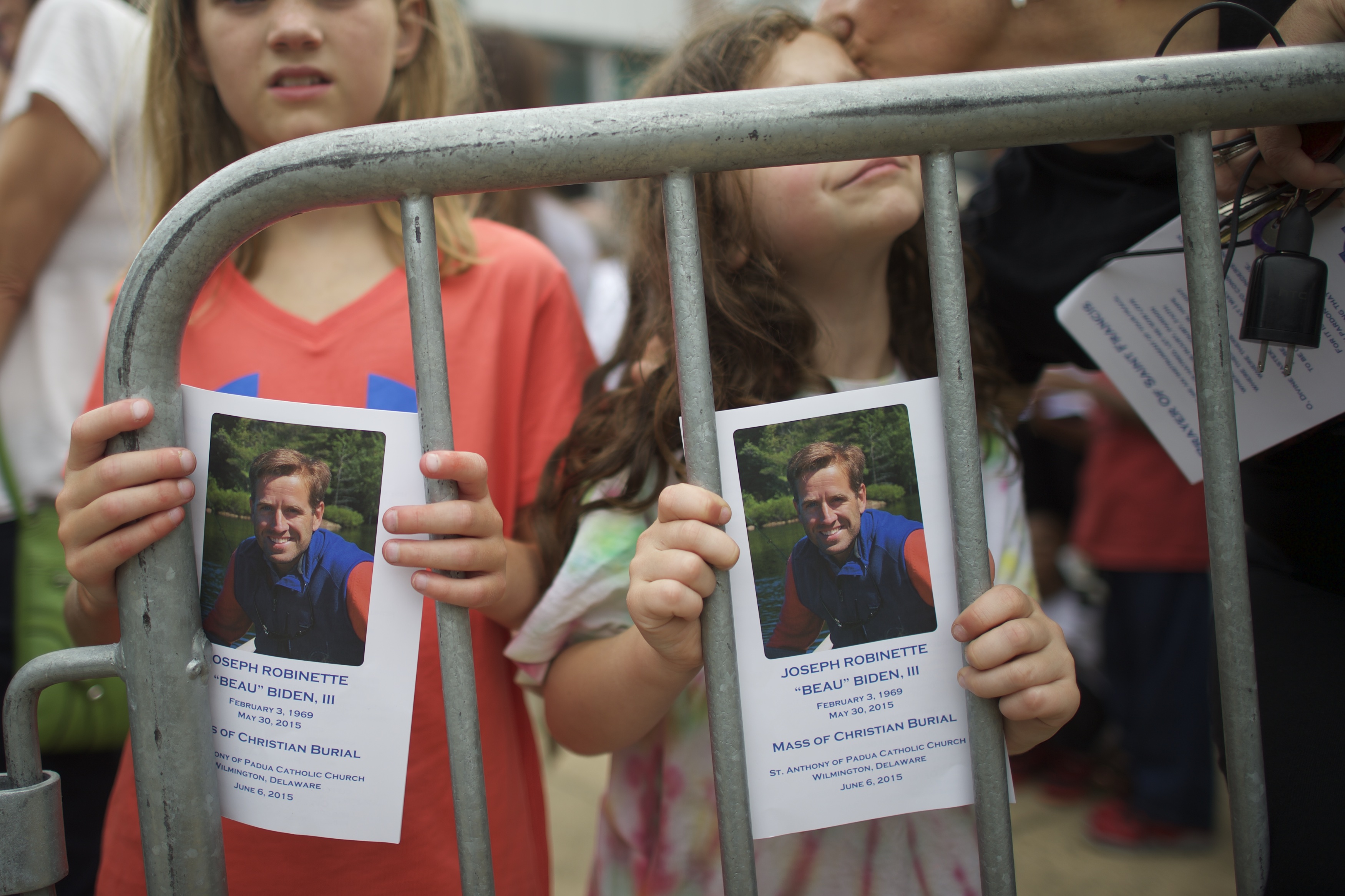 Mourners hold photos of Beau Biden as the hearse arrives for his funeral on June 6, 2015, in Wilmington, Delaware. | Source: Getty Images