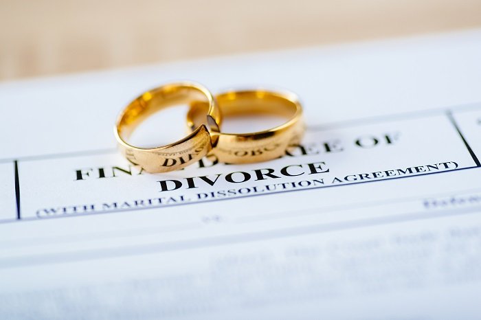 Anillos de bodas de oro sobre un documento de divorcio. | Foto: Shutterstock Anillos de bodas de oro sobre un documento de divorcio. | Foto: Shutterstock