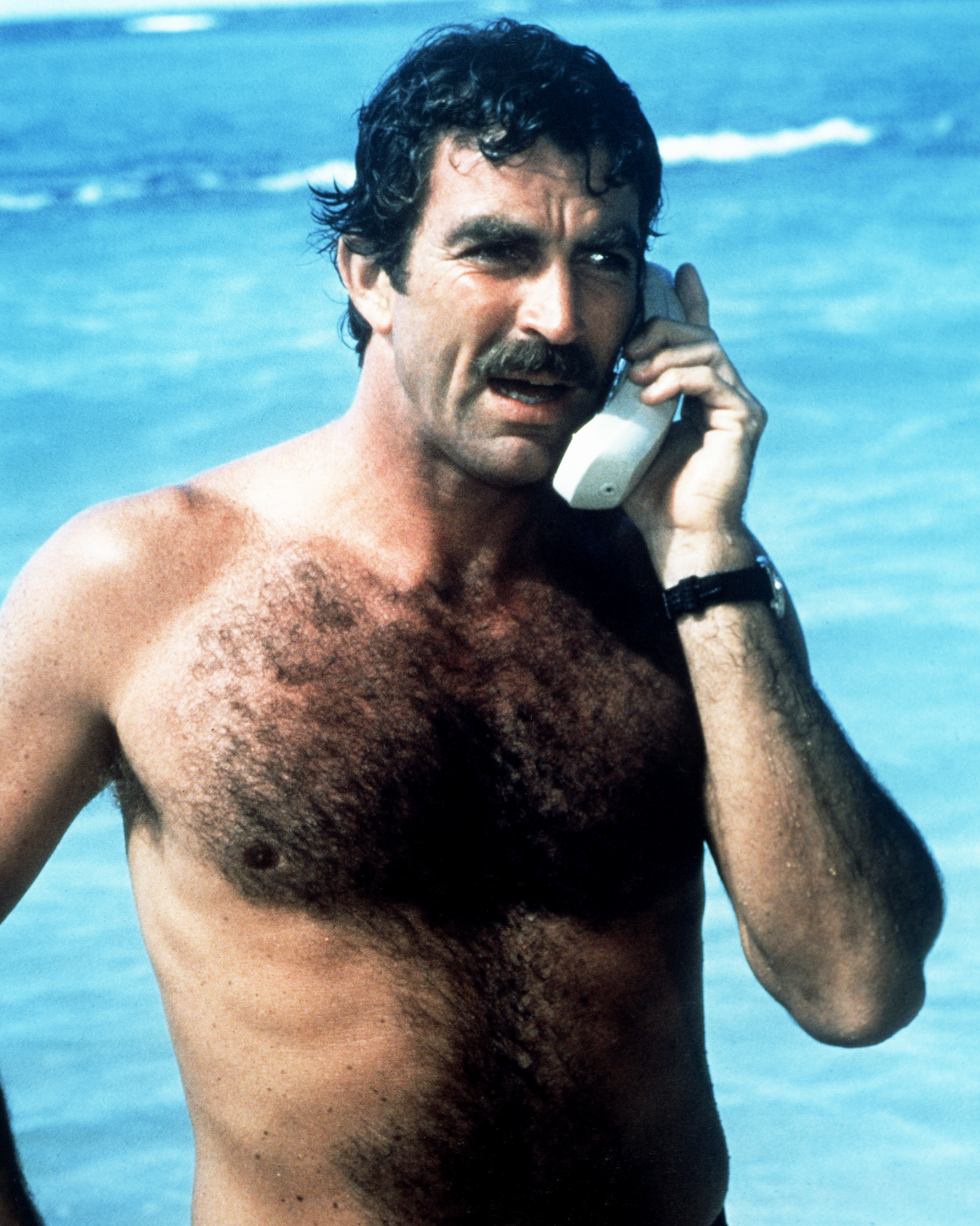 Nobody could convince her that the person on the other side wasn't Tom Selleck. This is the actor during his time as Thomas Magnum, shown here making a phone call from the beach in the TV series "Magnum P.I." circa 1985 | Source: Getty Images