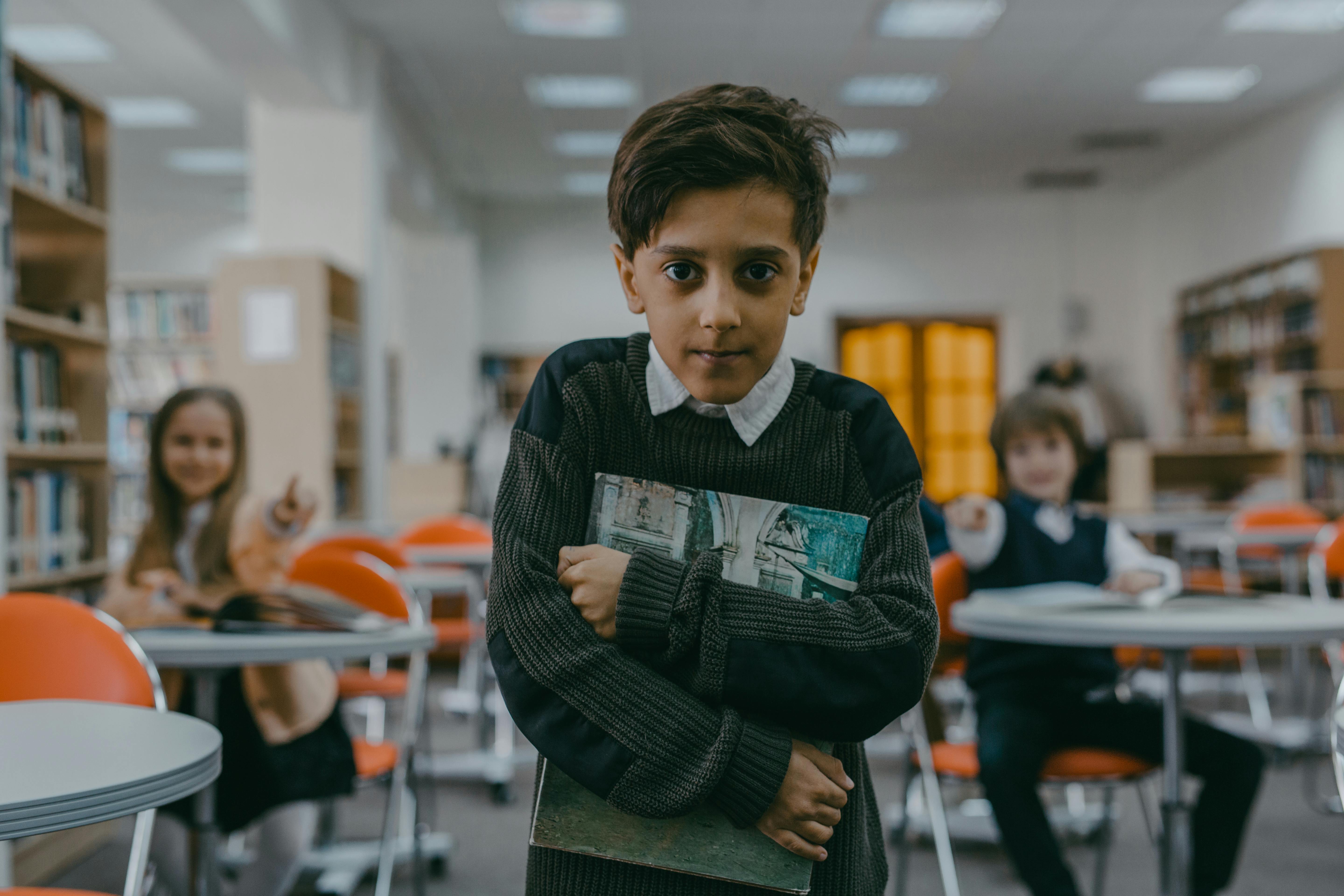 A child hugging a book with a small smile | Source: Pexels