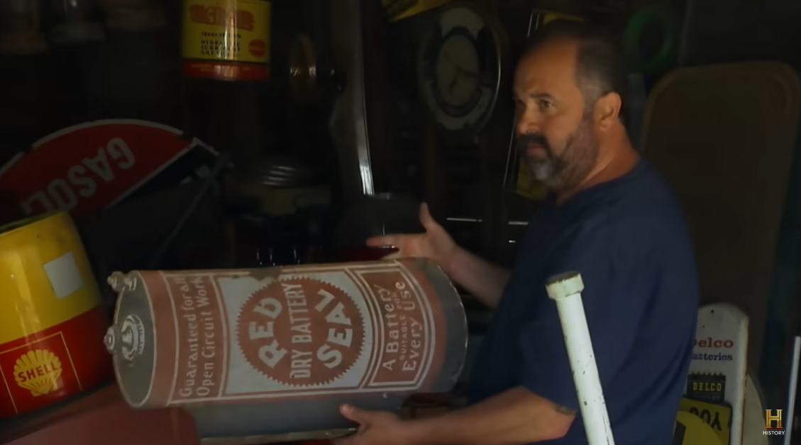 Frank Fritz holding a scrap metal piece shaped like a can on the TV show "American Pickers," shared on October 6, 2018 | Source: YouTube.com/HISTORY