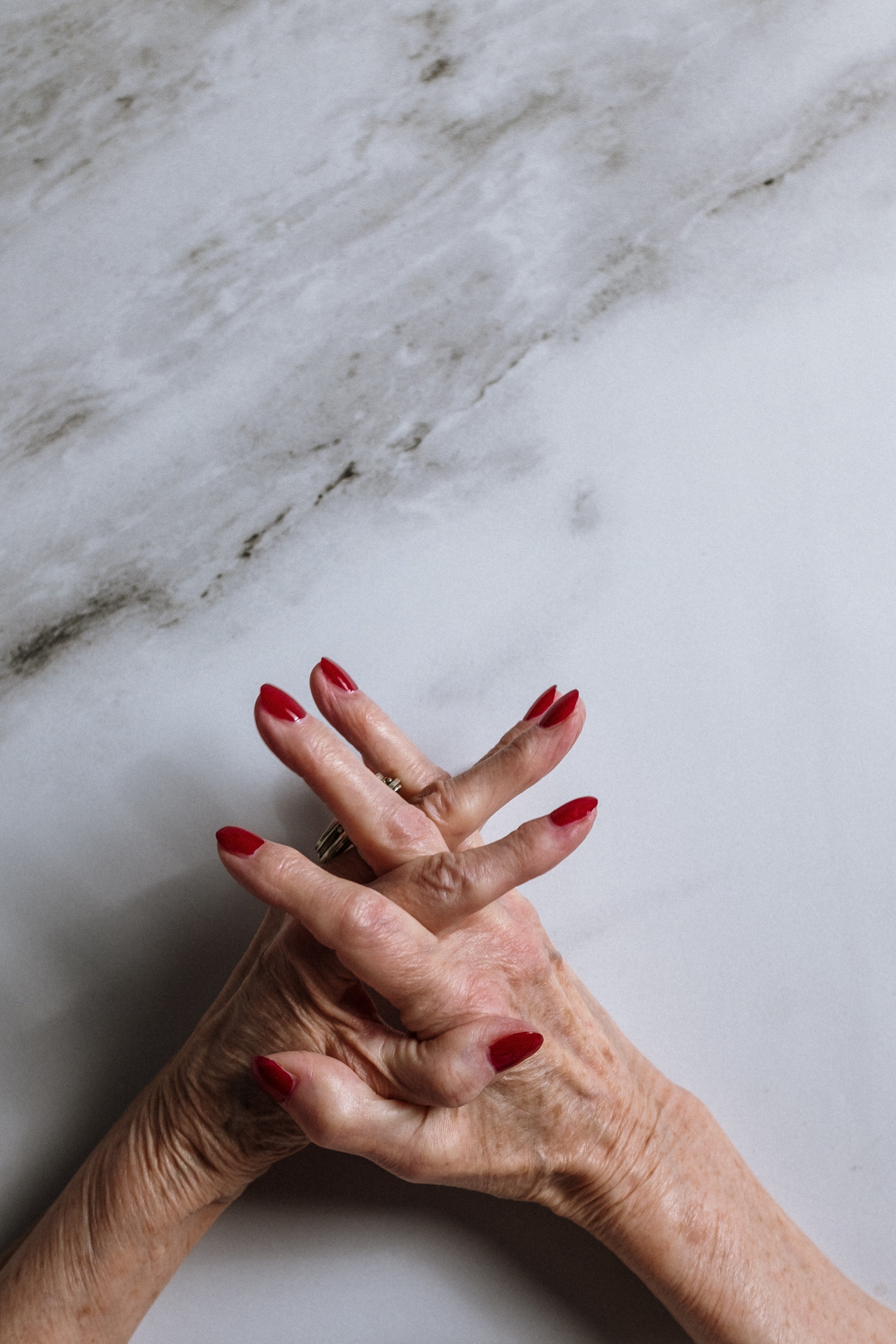 Las manos de una mujer mayor con los dedos cruzados. | Foto: Pexels