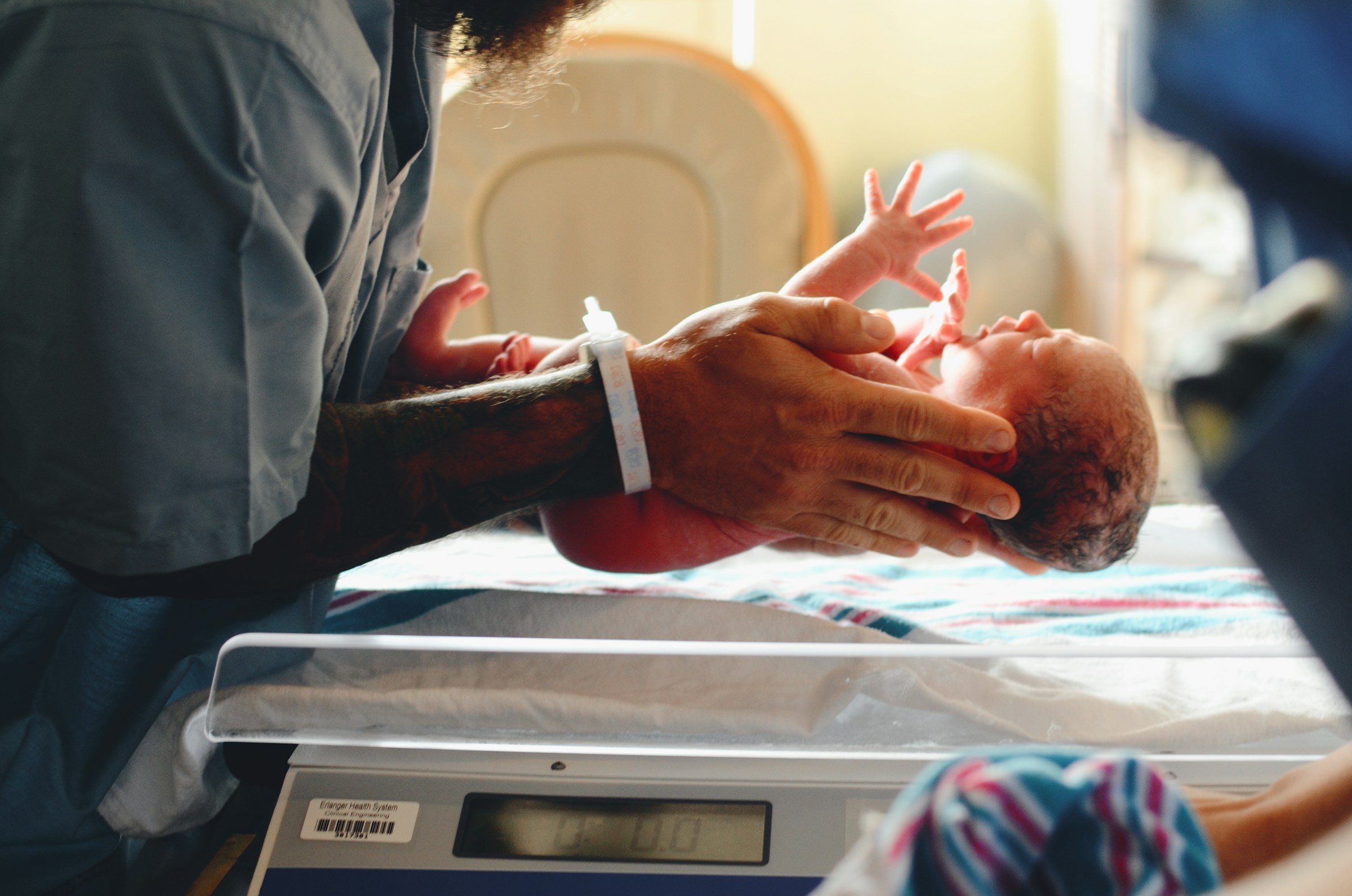 A doctor putting a newborn baby on scales | Source: Unsplash