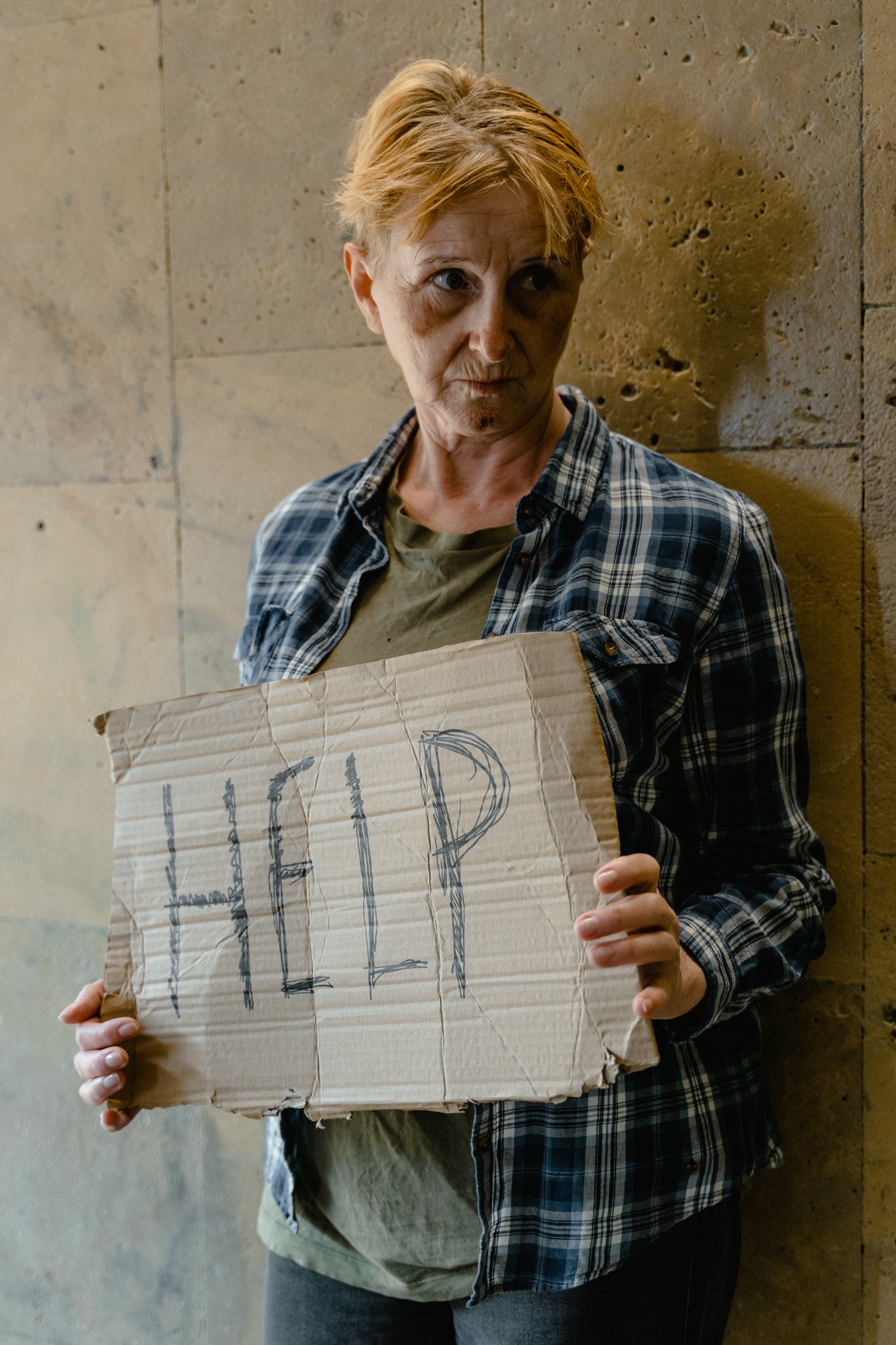Una mujer sin hogar sosteniendo un cartel que dice: "Ayuda". | Foto: Pexels
