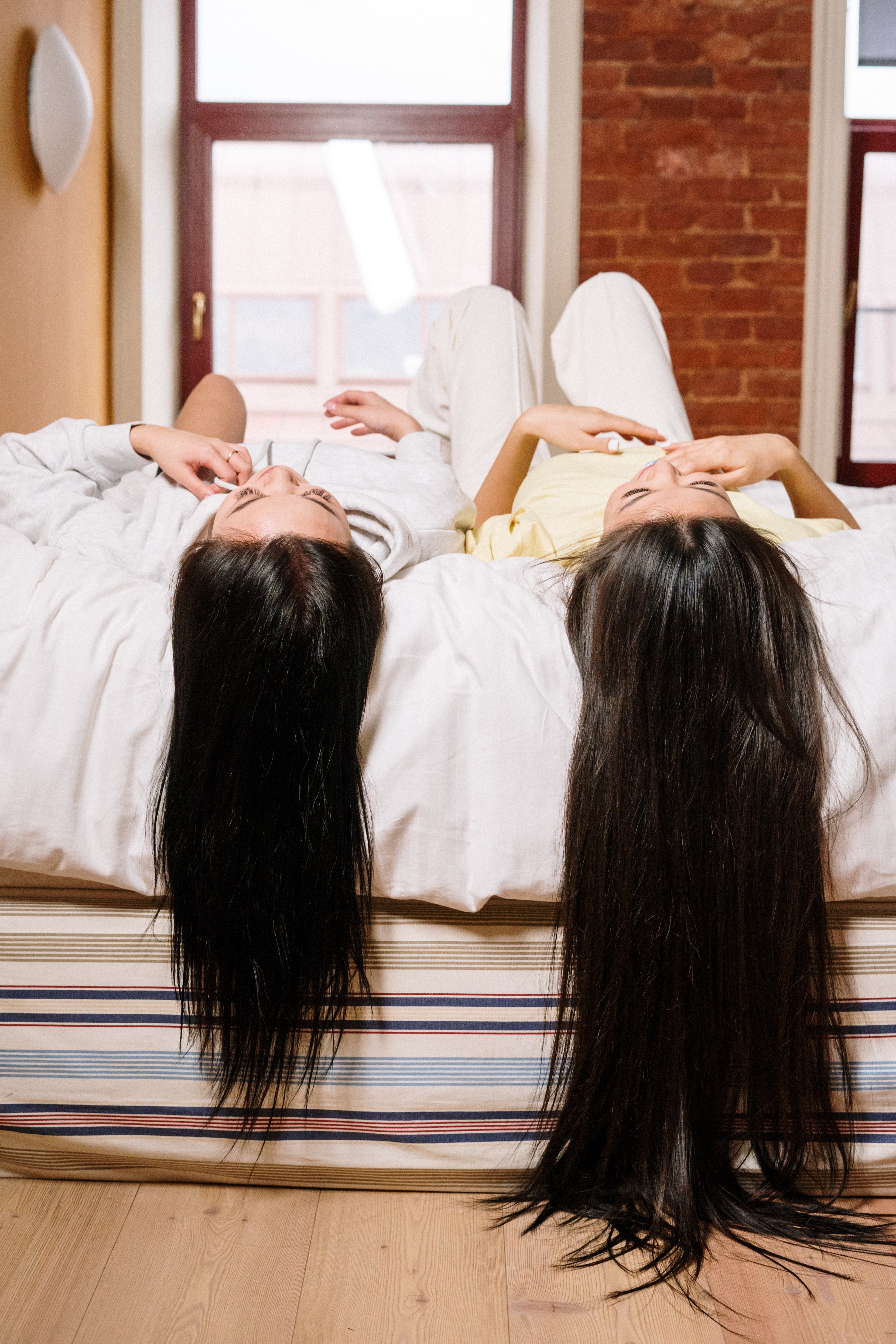 The woman lying on a bed with their hair dangling from the bed | Source: Pexels