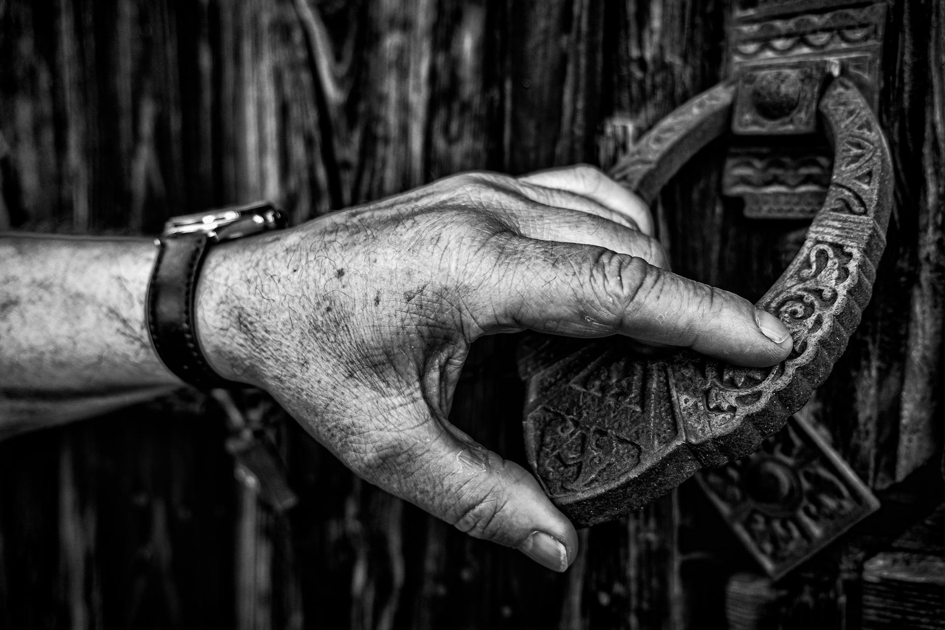 A hand holding a door knocker | Source: Pexels