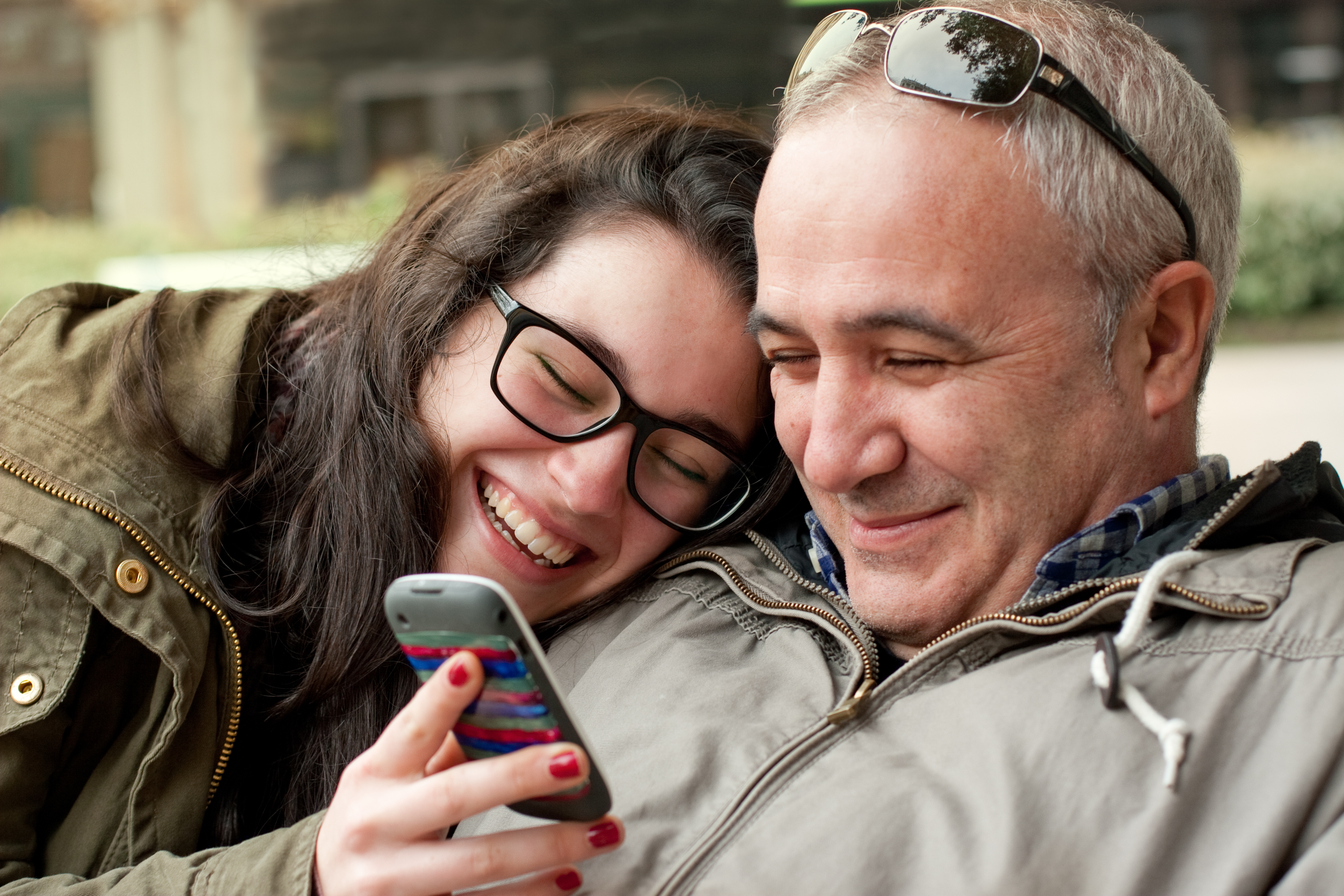 Una mujer ríe mientras enseña su teléfono móvil a un hombre. | Foto: Shutterstock