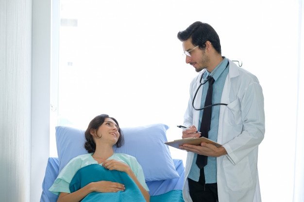 Mujer en cama de hospital conversando con un doctor. | Foto: Freepik