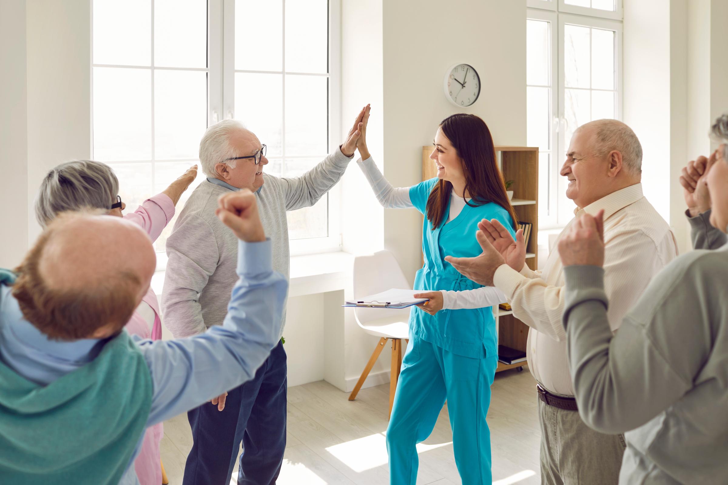 Friendly nurse giving a "Hi five" to seniors at a nursing home | Source: Shutterstock