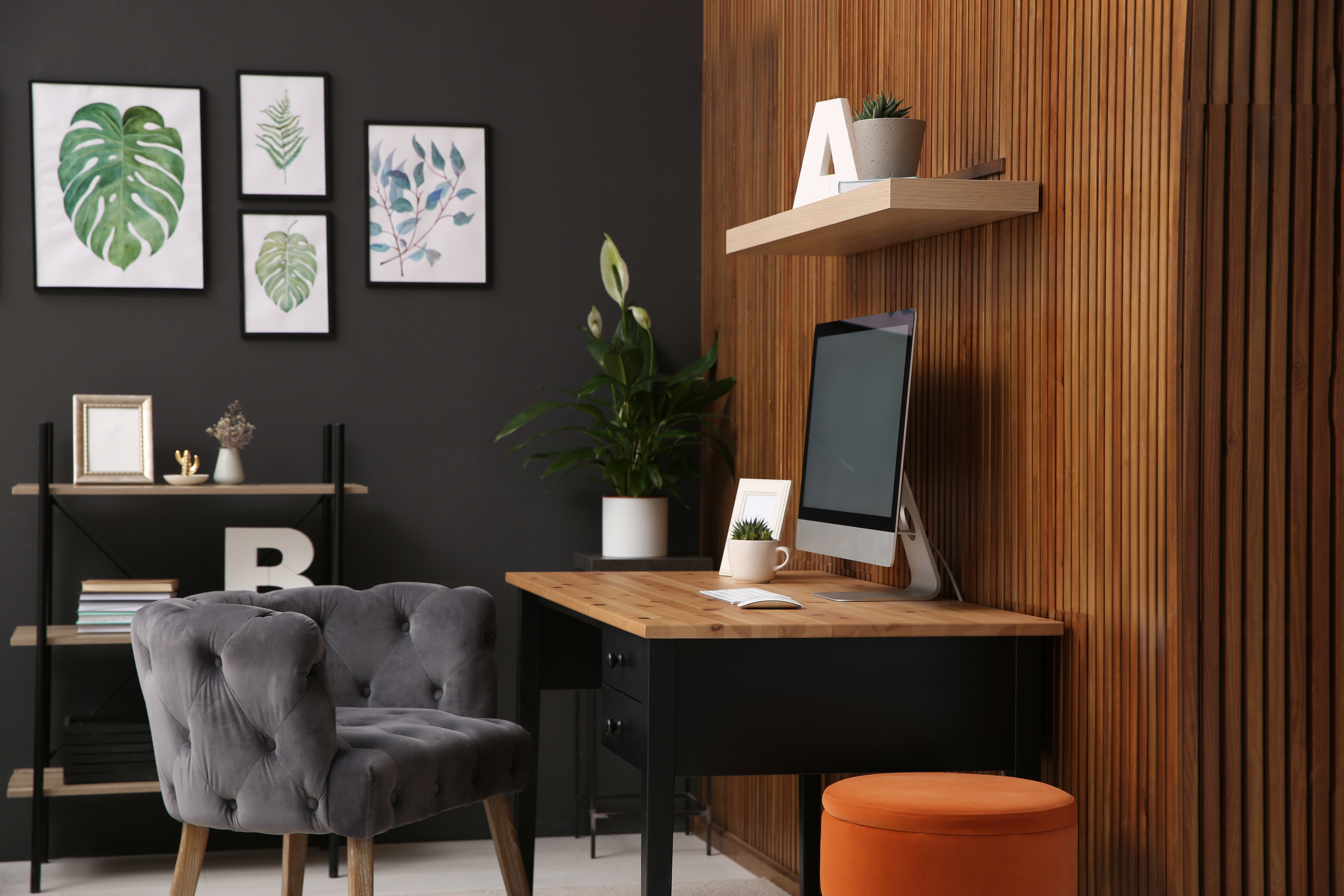 Comfortable workplace with computer near wooden wall in stylish room interior. Home office design. | Source: Shutterstock