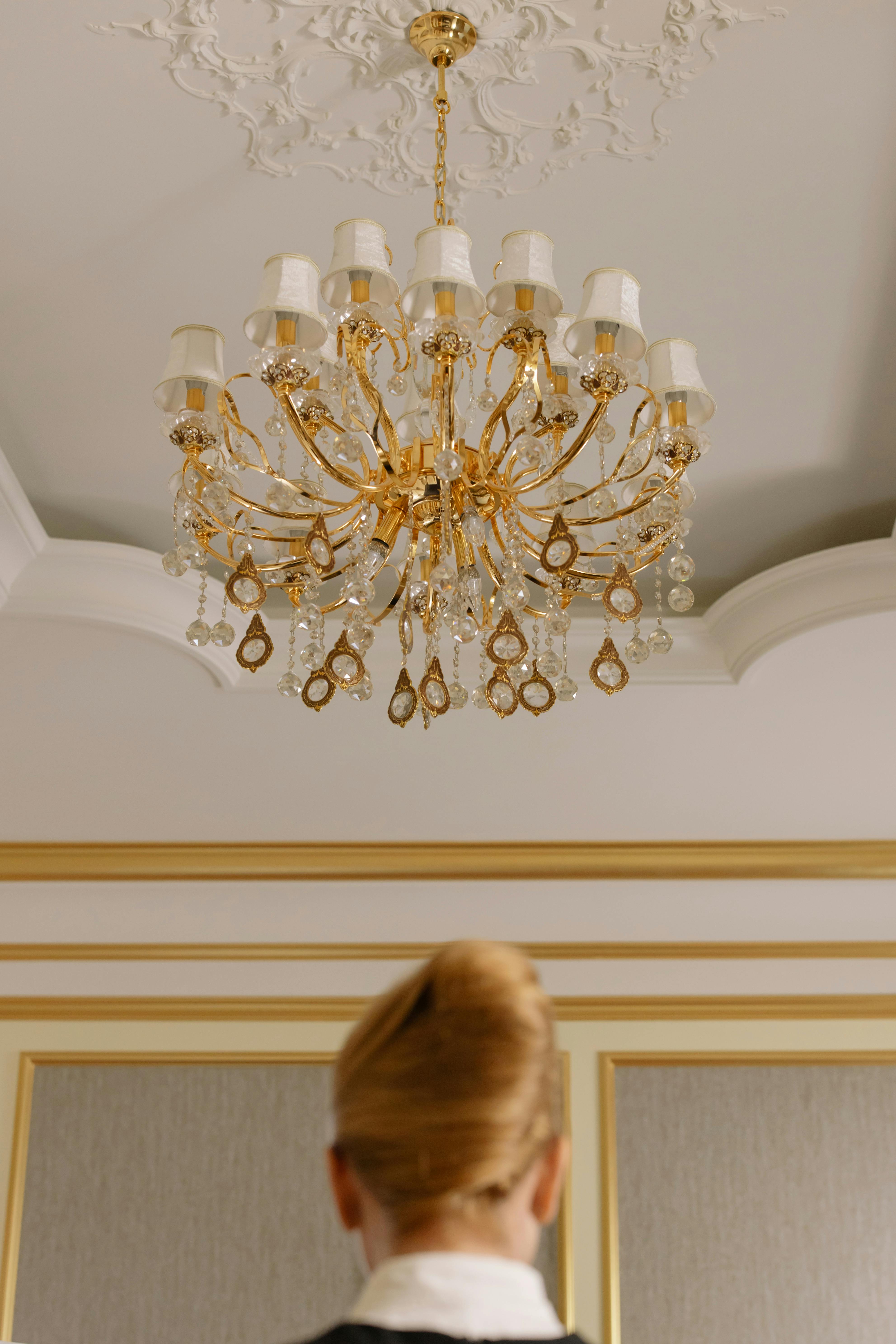 Woman standing under a chandelier of a hotel room | Source: Pexels
