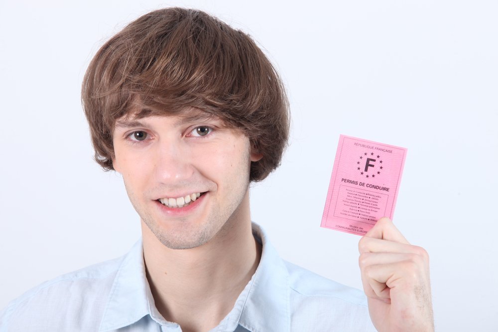 Un jeune homme montrant son permis de conduire français. | Shutterstock Un jeune homme montrant son permis de conduire français. | Shutterstock