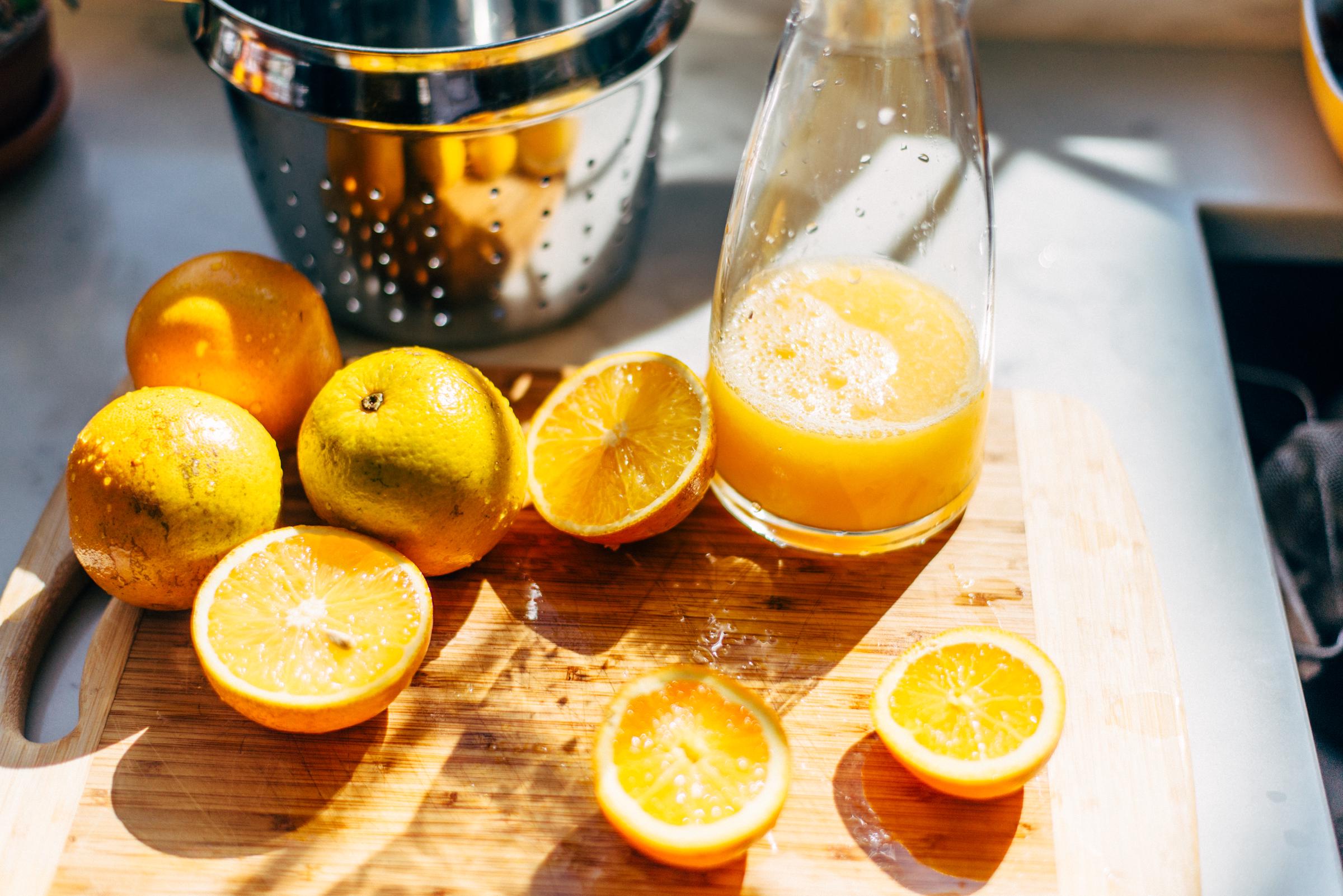 Oranges and freshly-squeezed orange juice on a cutting board | Source: Getty Images