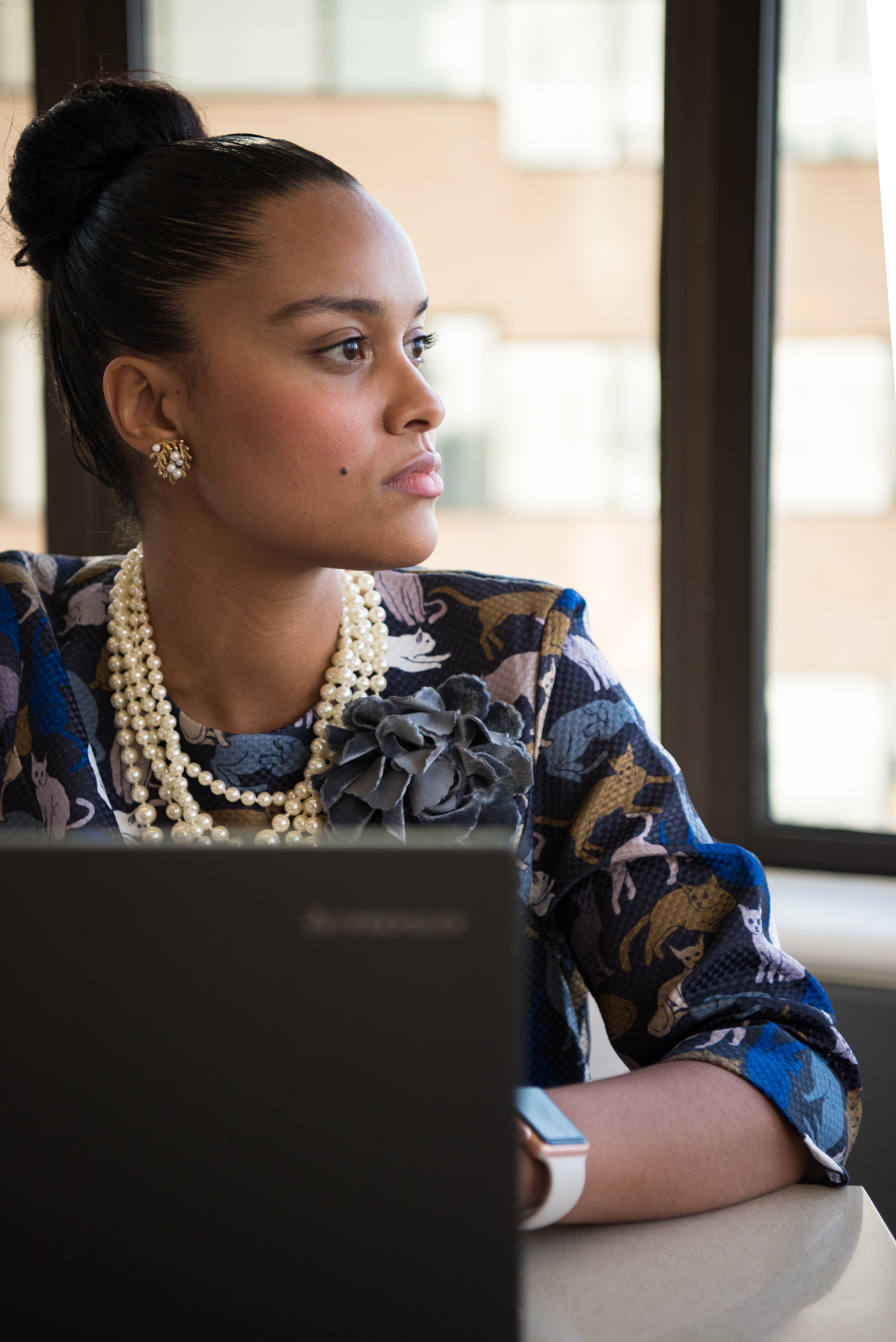 Una mujer elegante mirando hacia un lado frente a una computadora portátil. | Foto: Unsplash