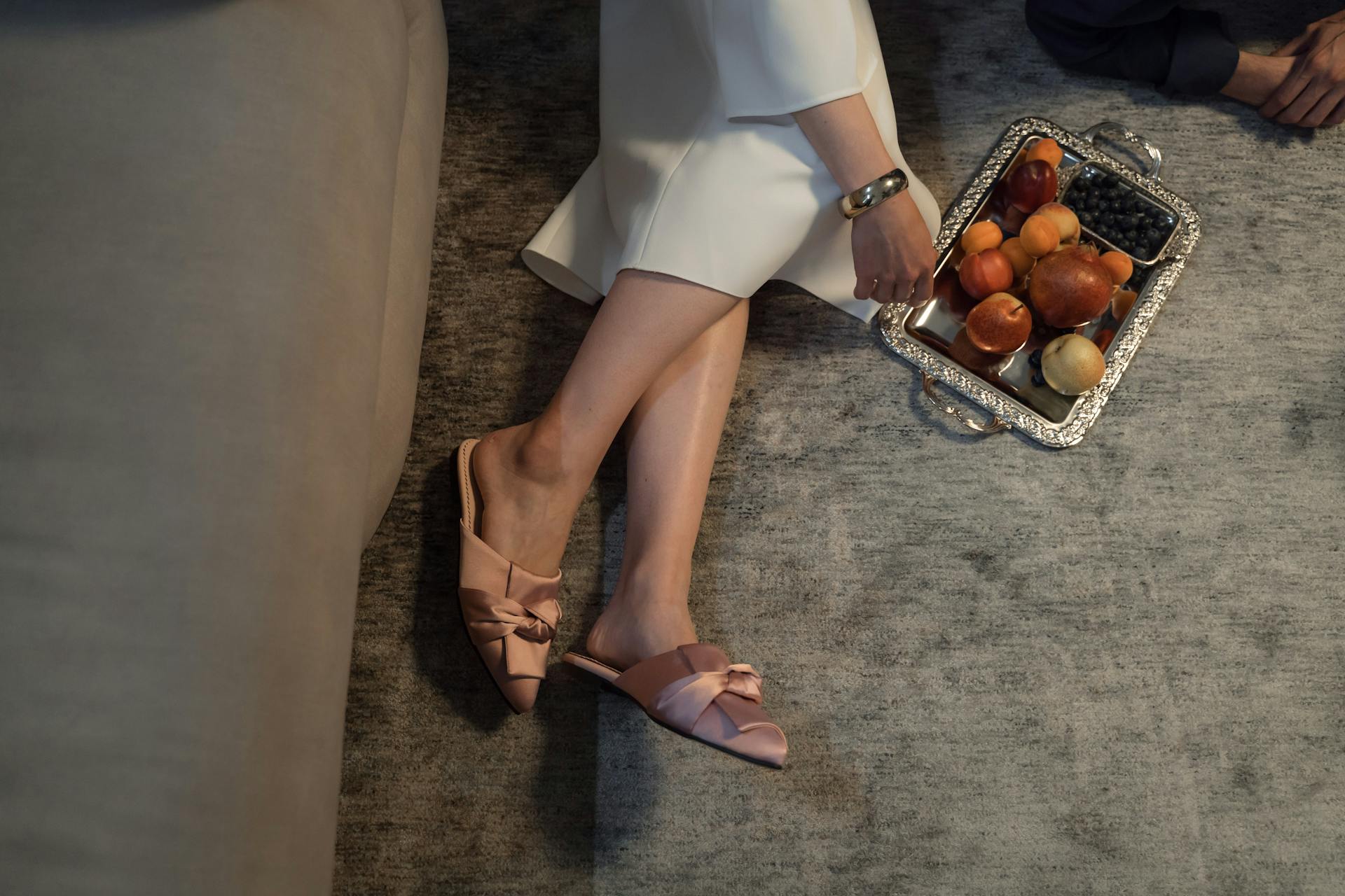 A closeup of a woman wearing slippers while lying next to a fruit basket at home | Source: Pexels