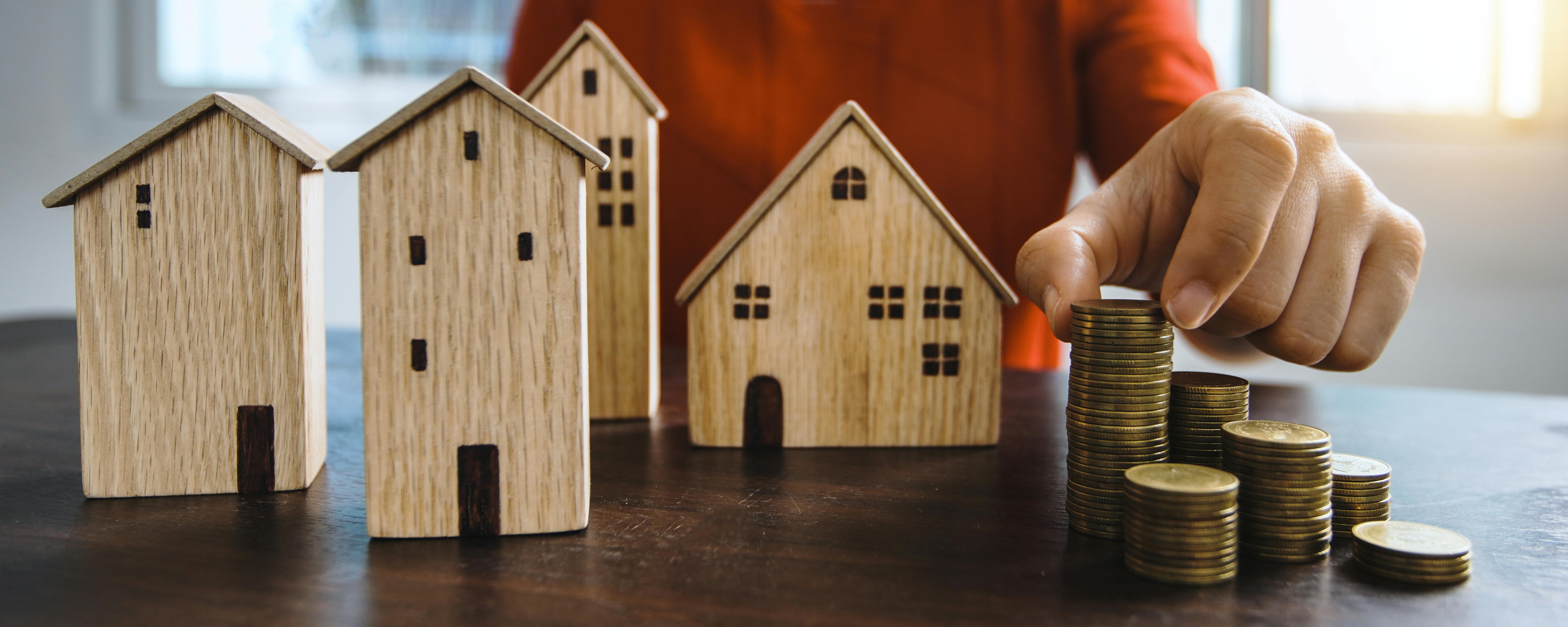 A wooden house and a person stacking coins | Source: Pexels