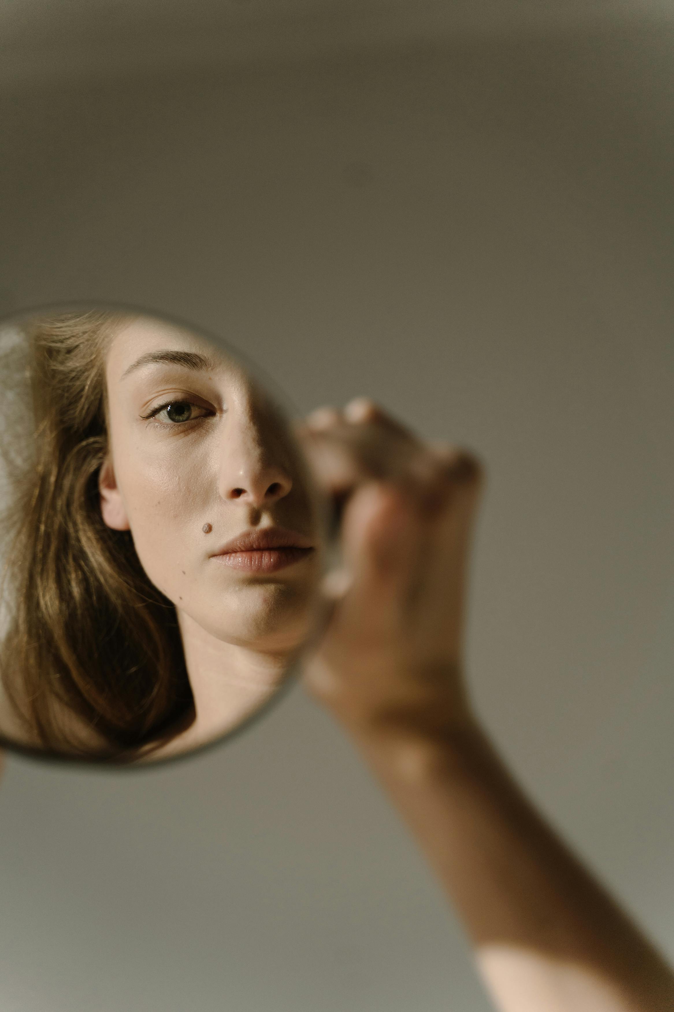 A woman looking at her reflection in a mirror | Source: Pexels