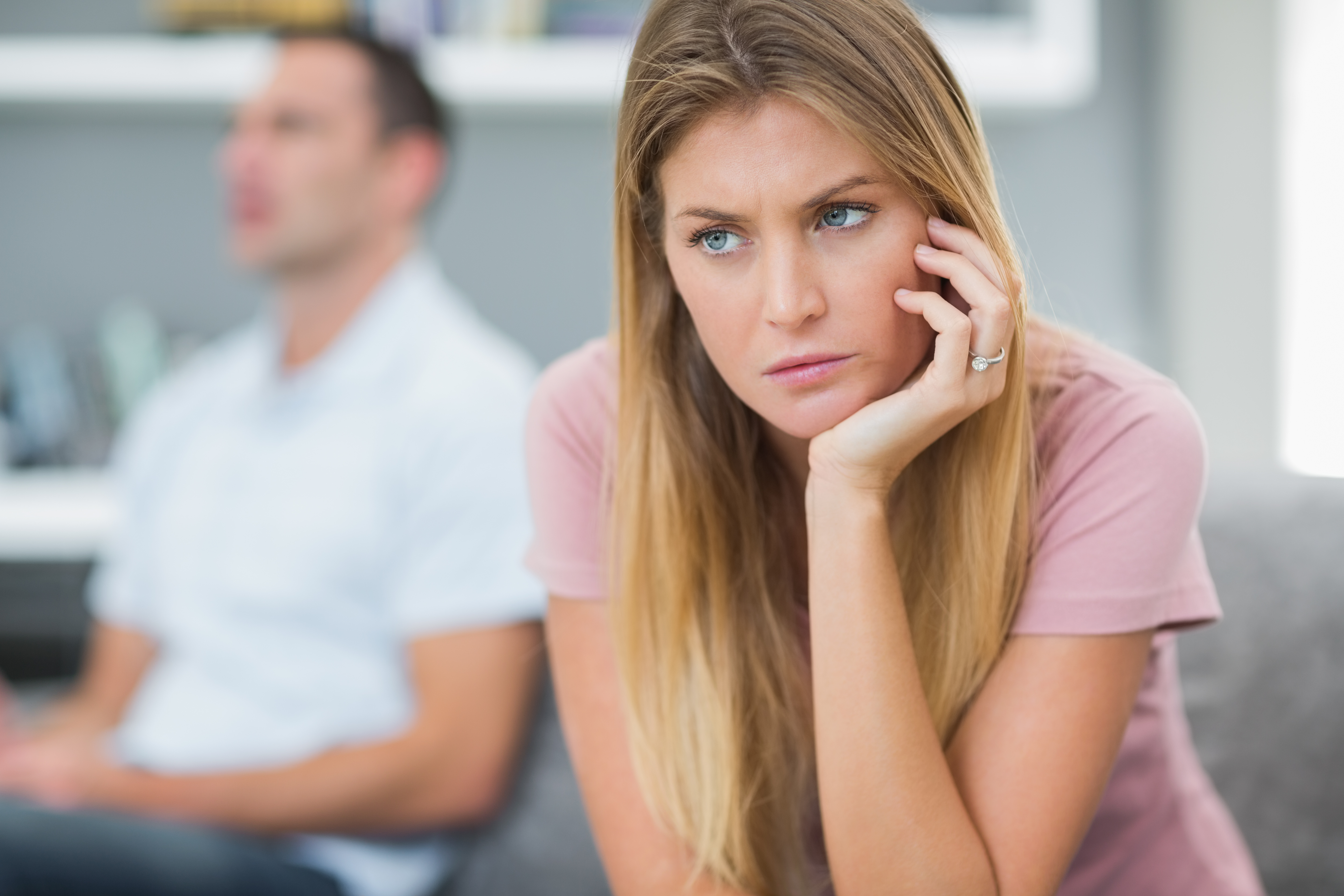 Woman looking upset while the man in the background seems unbothered | Source: Shutterstock