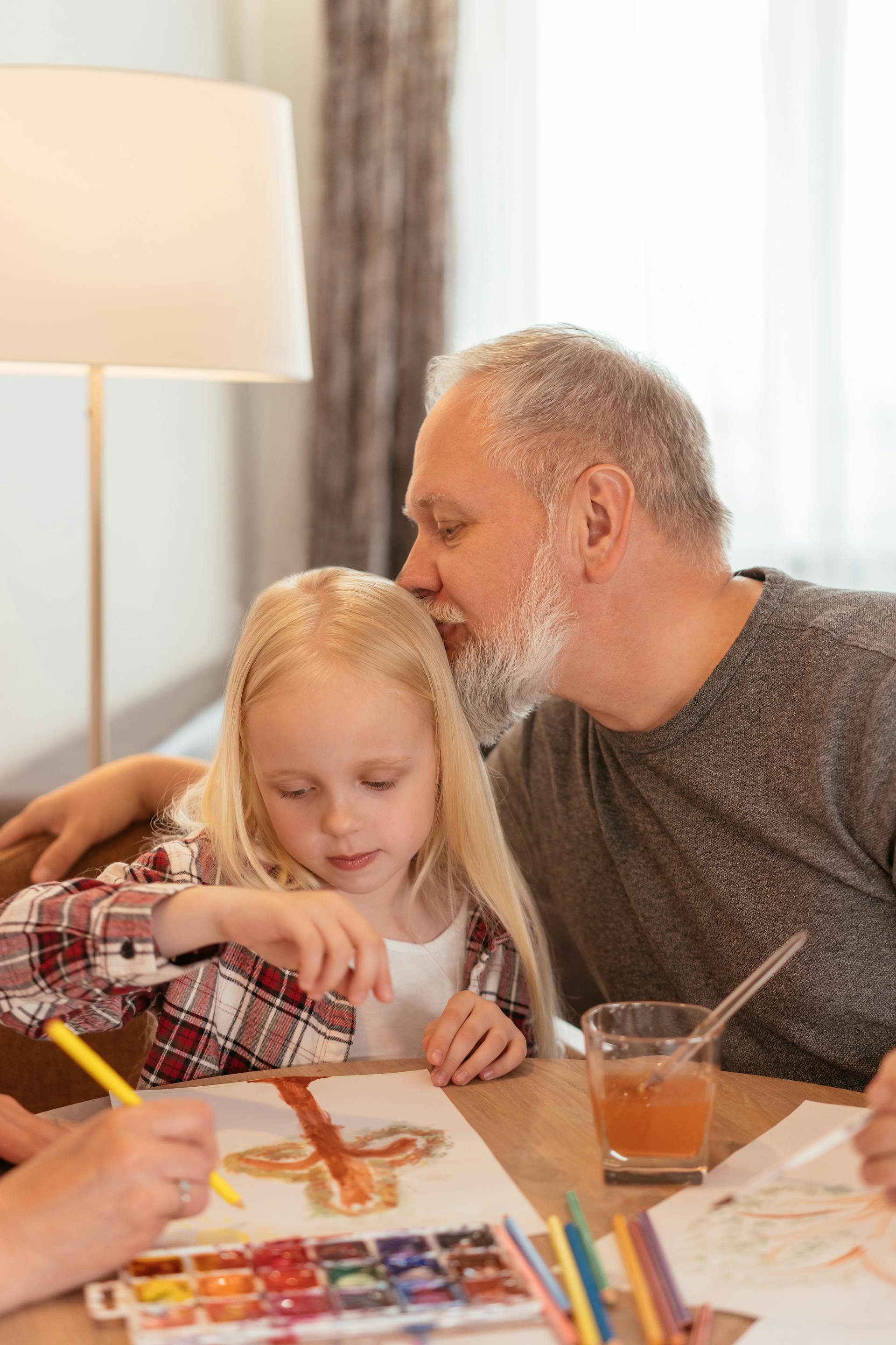 A grandfather kissing his granddaughter on the forehead | Source: Pexels