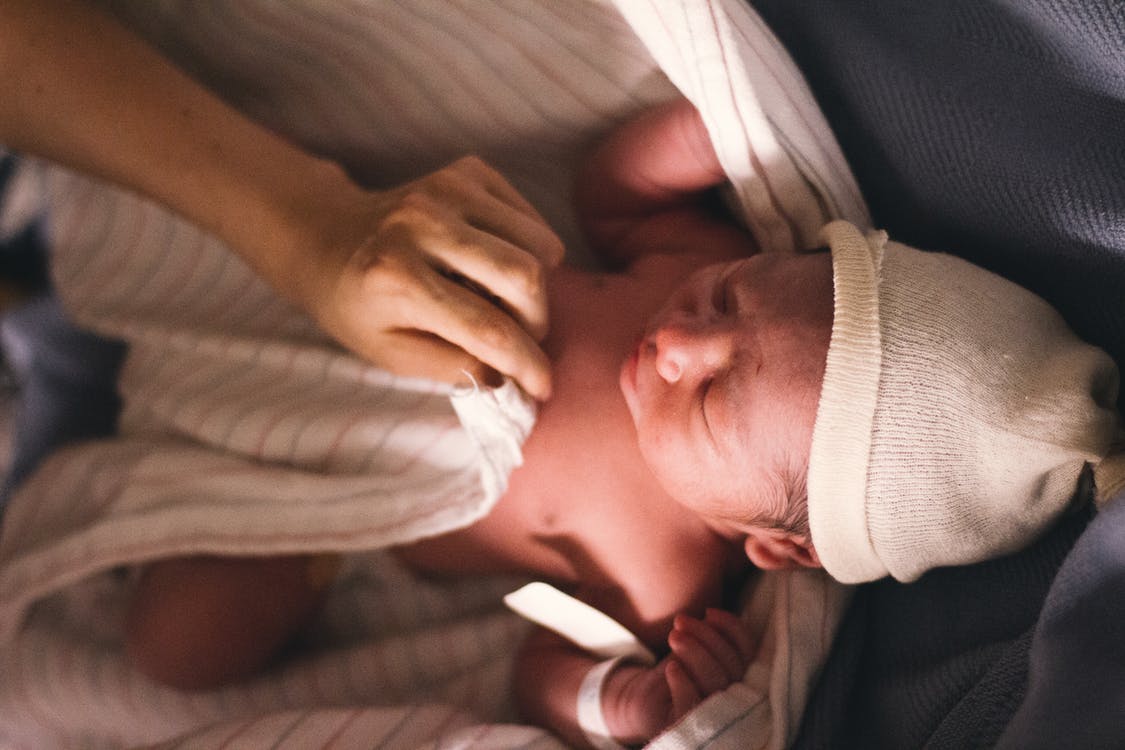Una persona cubriendo a una bebé recién nacida con una manta. | Foto: Pexels