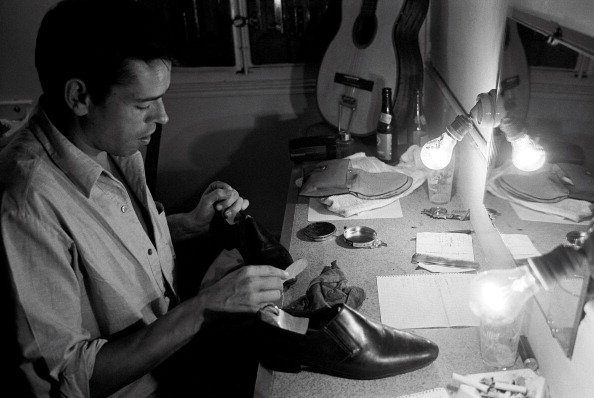 Le chanteur Jacques Brel dans sa loge cirant ses chaussures. |Photo : Getty Images