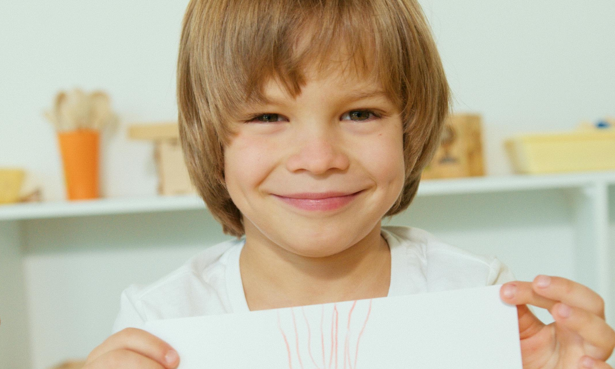 A smiling boy holds up a drawing | Source: Pexels