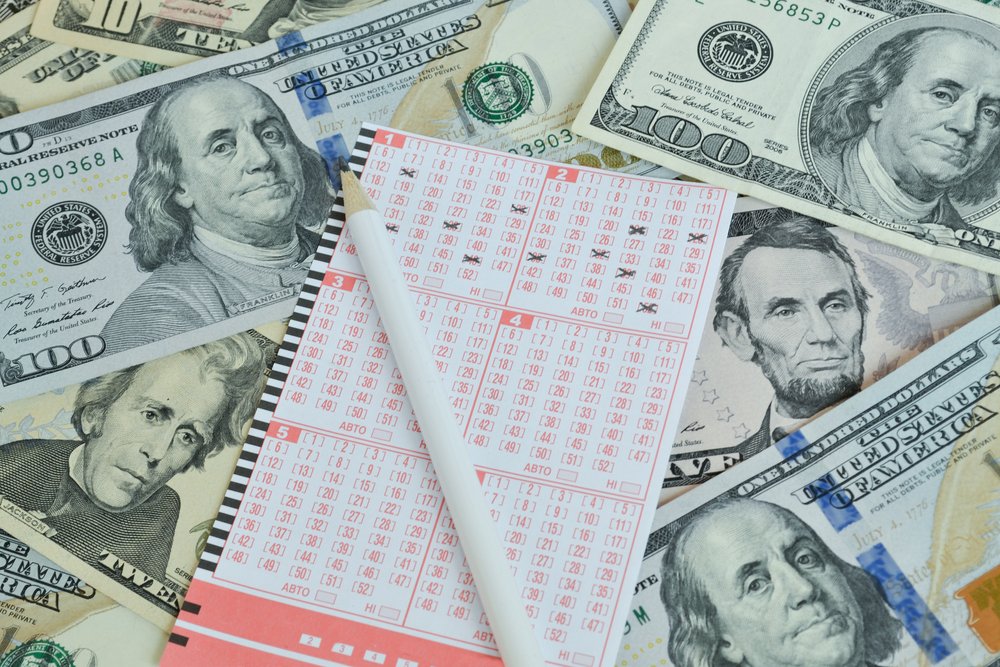 Lápiz y billete de lotería sobre una cama de dinero en efectivo. | Foto: Shutterstock
