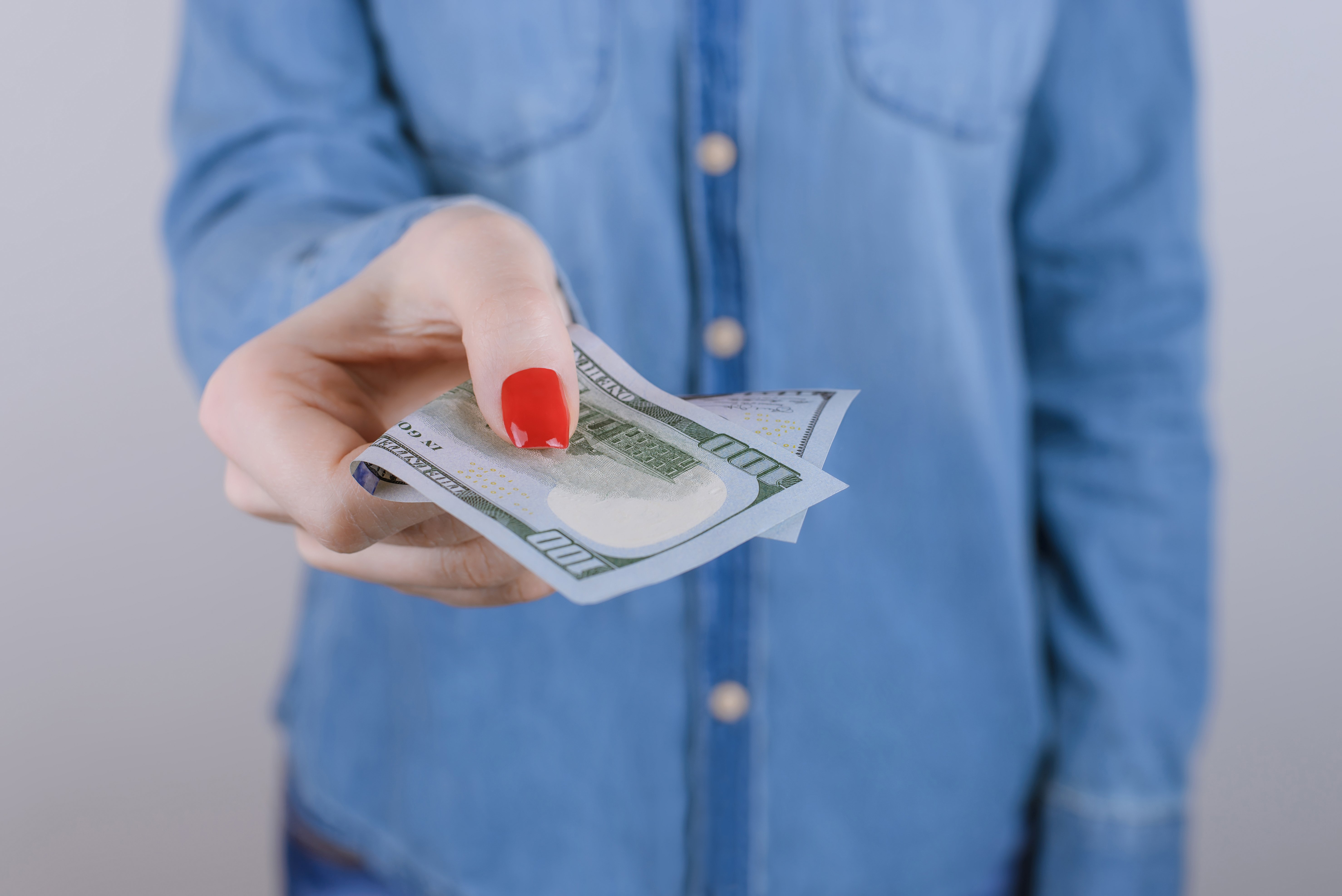 Mujer entrega billete de 100 dólares. | Foto: Shutterstock
