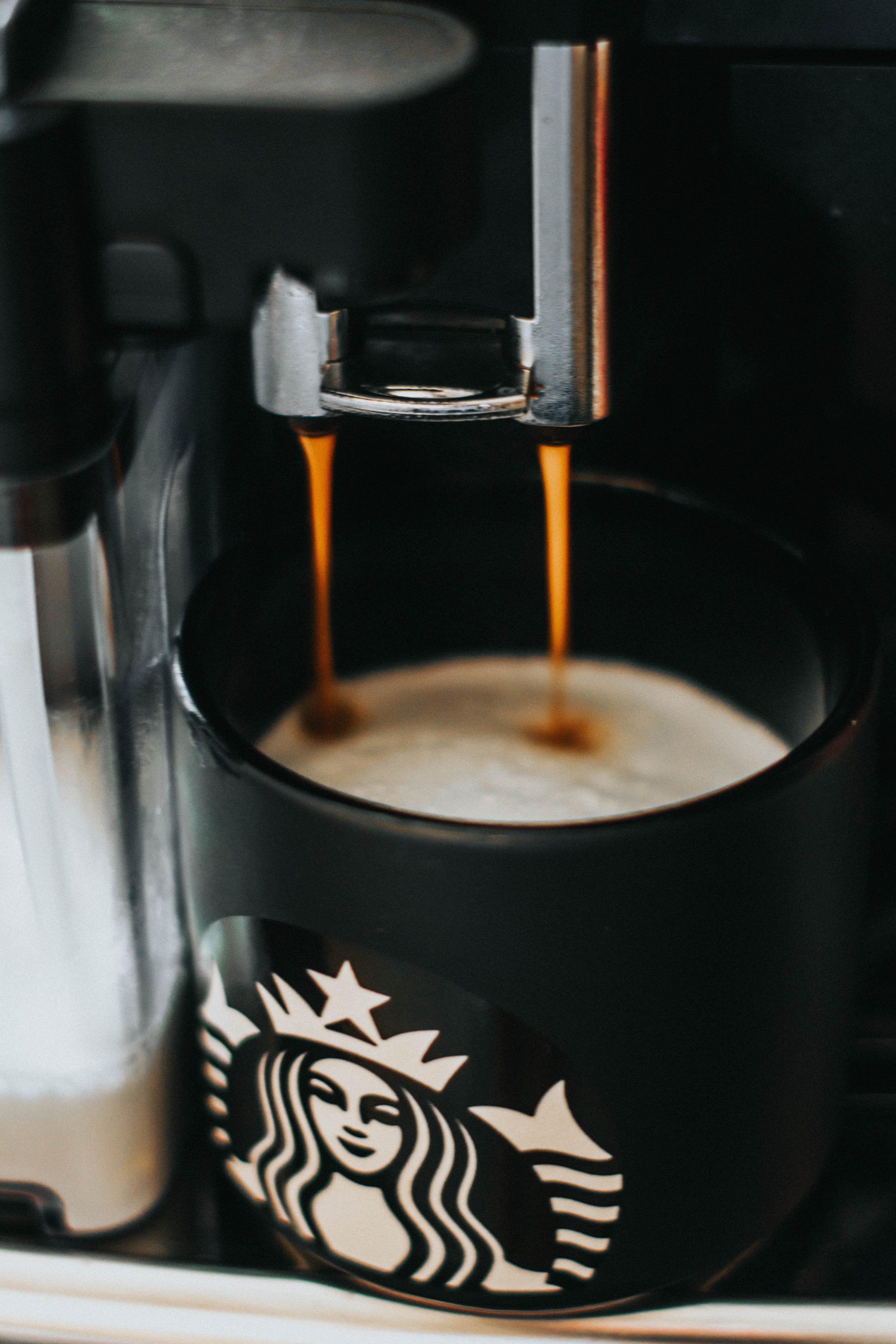 A barista makes coffee for a customer in one of their Starbucks coffee mugs | Photo: Unsplash/Sebastian Dumitru