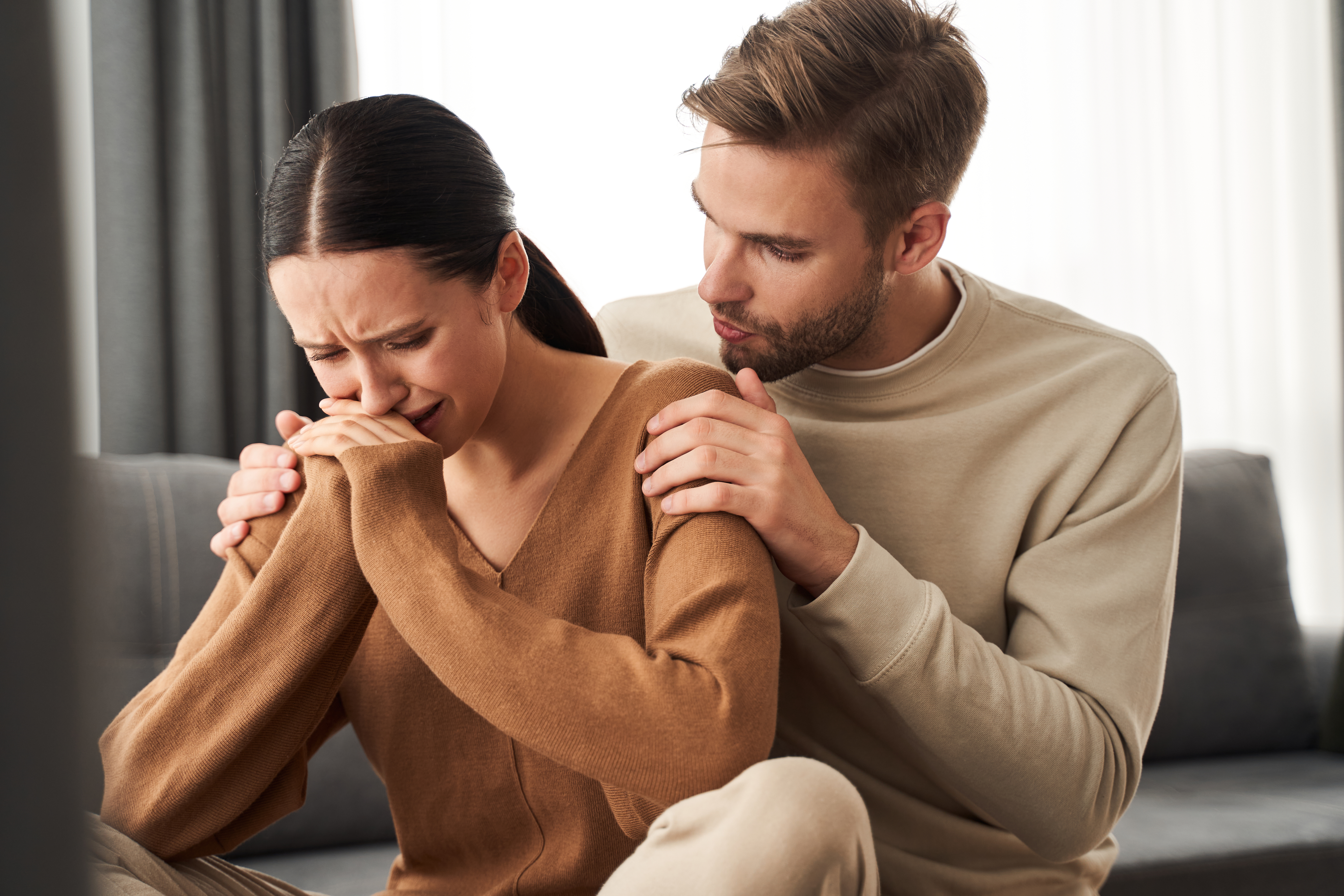 A husband trying to calm down his crying wife | Source: Shutterstock