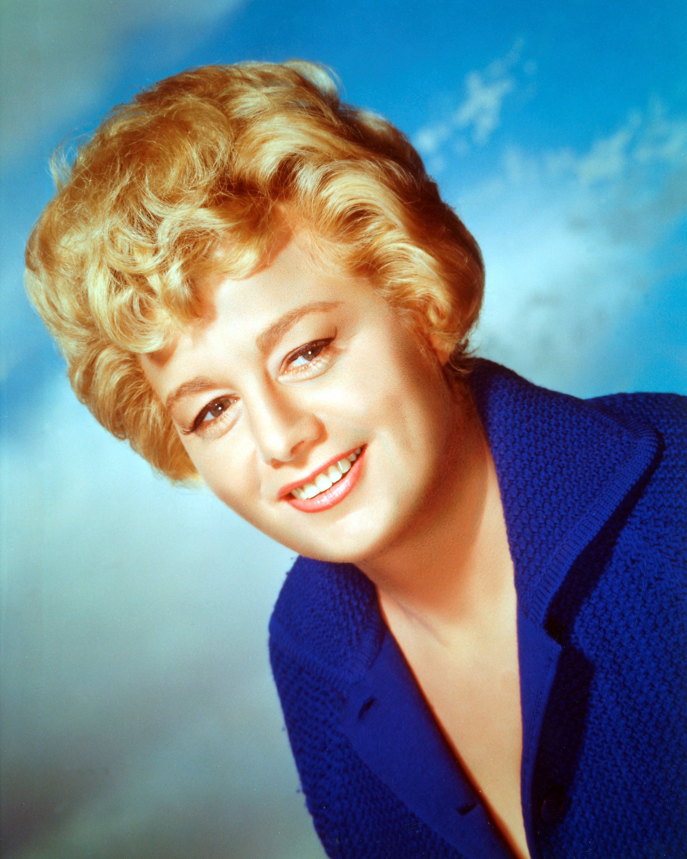 Shelley Winters (1920-2006), US actress, smiling and wearing a dark blue blouse in a studio portrait, against a background of blue sky and clouds, circa 1965. | Source: Getty Images
