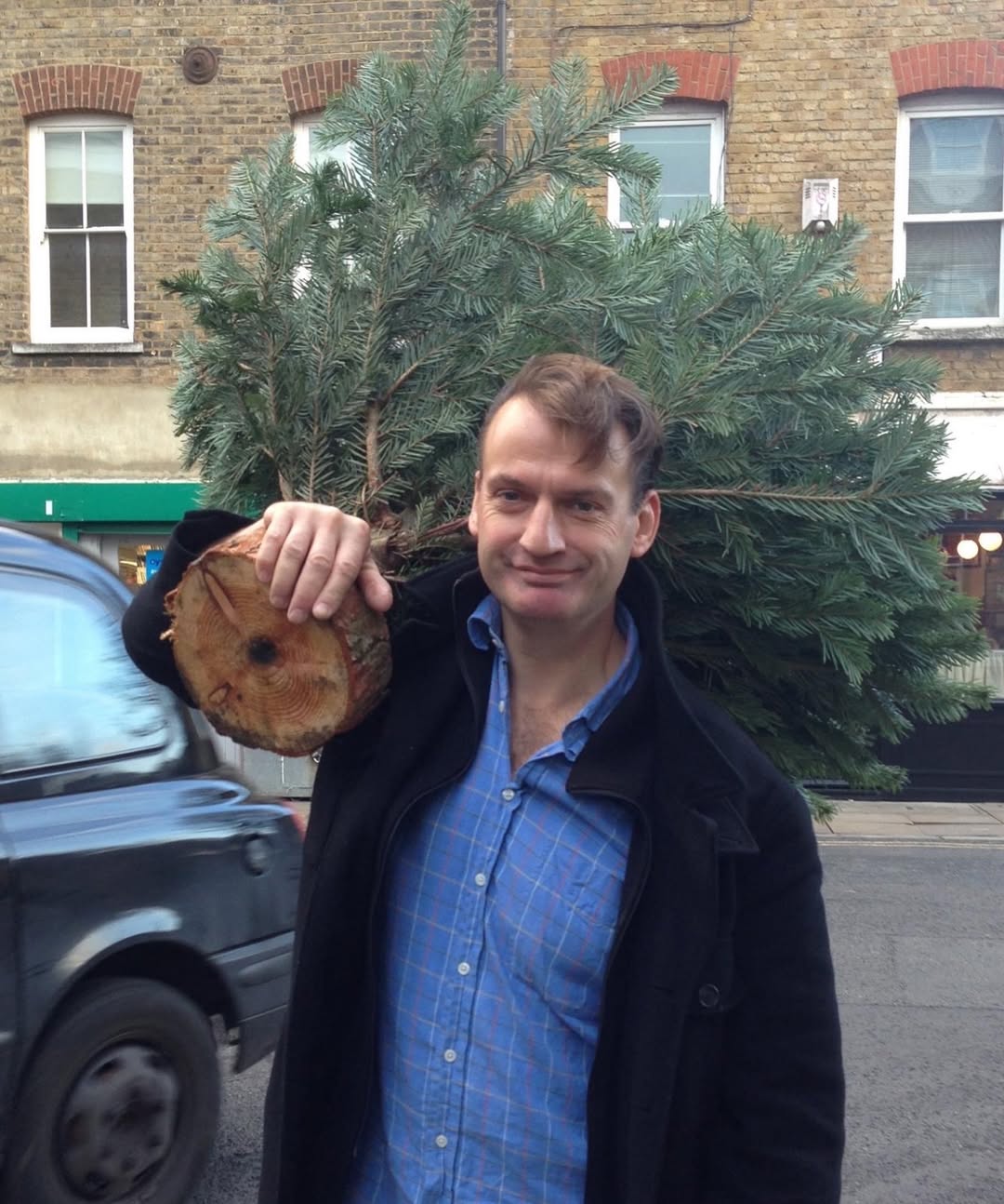 Carrying Christmas home. With a grin and a fir tree slung over his shoulder, Simon brings festive spirit to the street — the kind of memory that lives forever in the scent of pine and laughter. | Source: Instagram/douglasbooth
