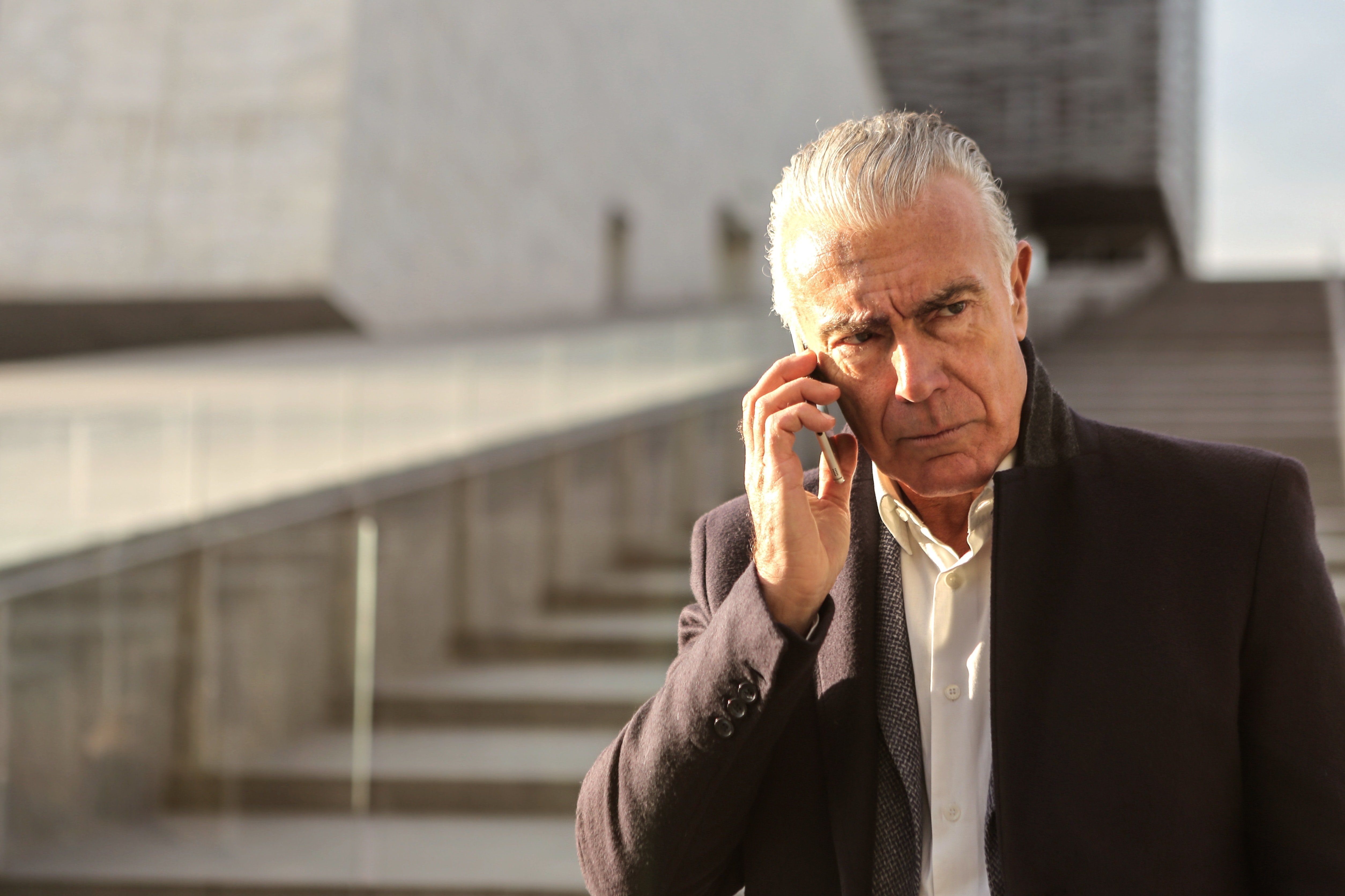 Un hombre mayor bajando unas escaleras mientras habla a través de un teléfono celular. | Foto: Pexels