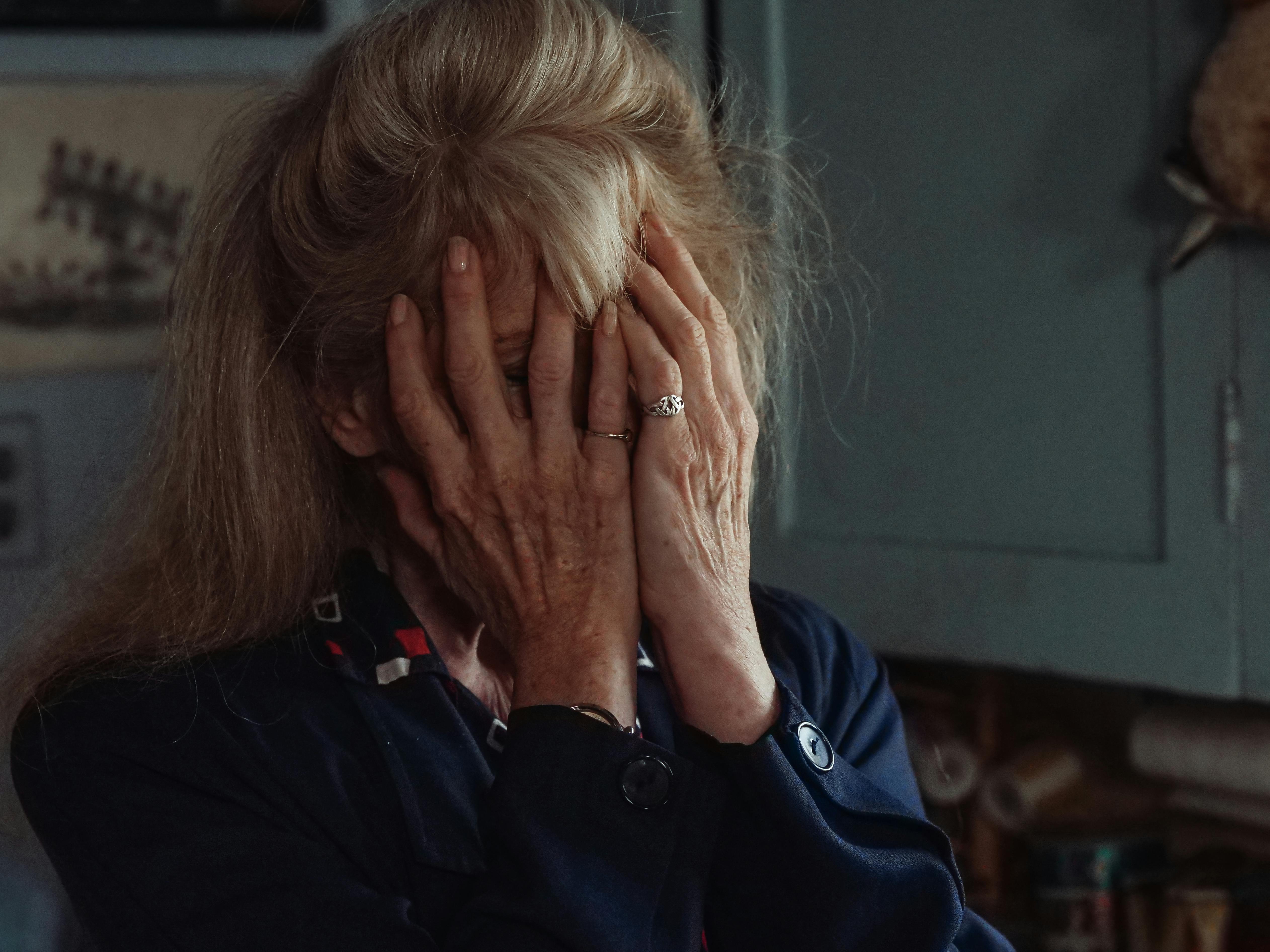 An elderly woman covering her face with her palms | Source: Pexels