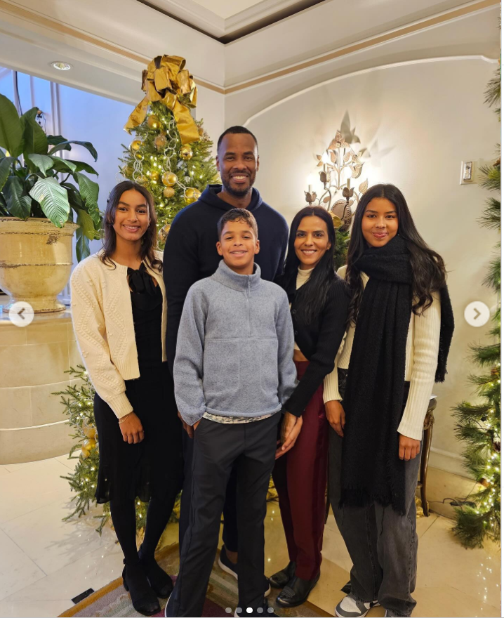 Jason Collins poses with members of his family in front of a decorated Christmas tree inside a warmly lit hotel lobby during a holiday gathering. | Source: Instagram/jasoncollins_98