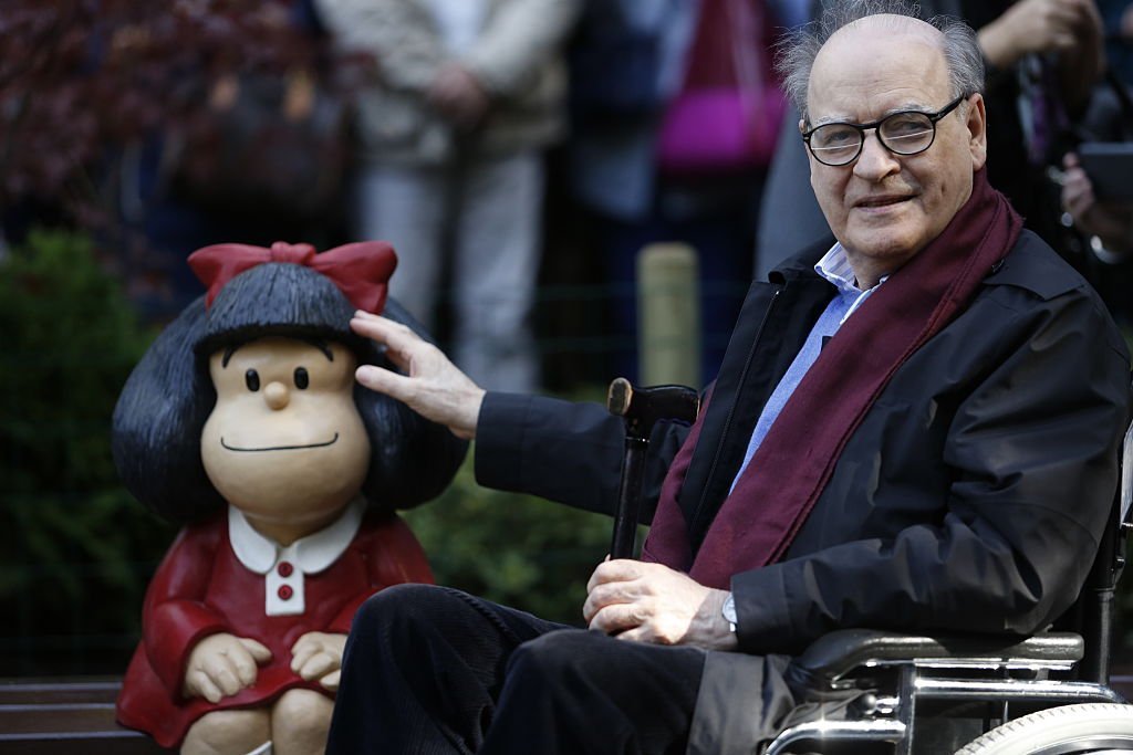 Le dessinateur Joaquin Salvador Lavado, alias Quino, pose à côté d'une sculpture de sa créature Mafalda au parc de San Francisco le 23 octobre 2014 à Oviedo, en Espagne. | Photo : Getty Images