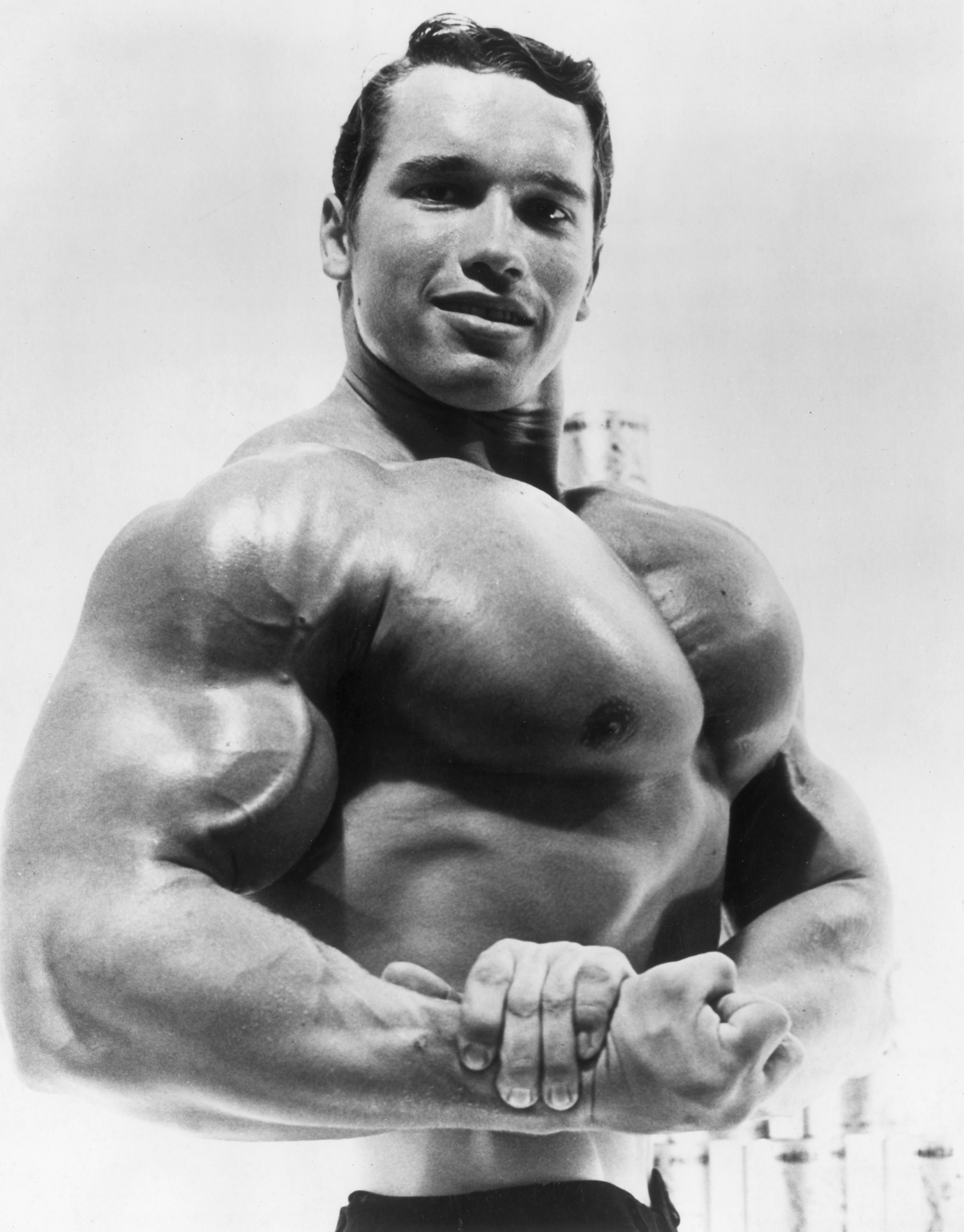 Arnold Schwarzenegger flexing his torso in an advertisement for a German protein product in 1967 | Source: Getty Images