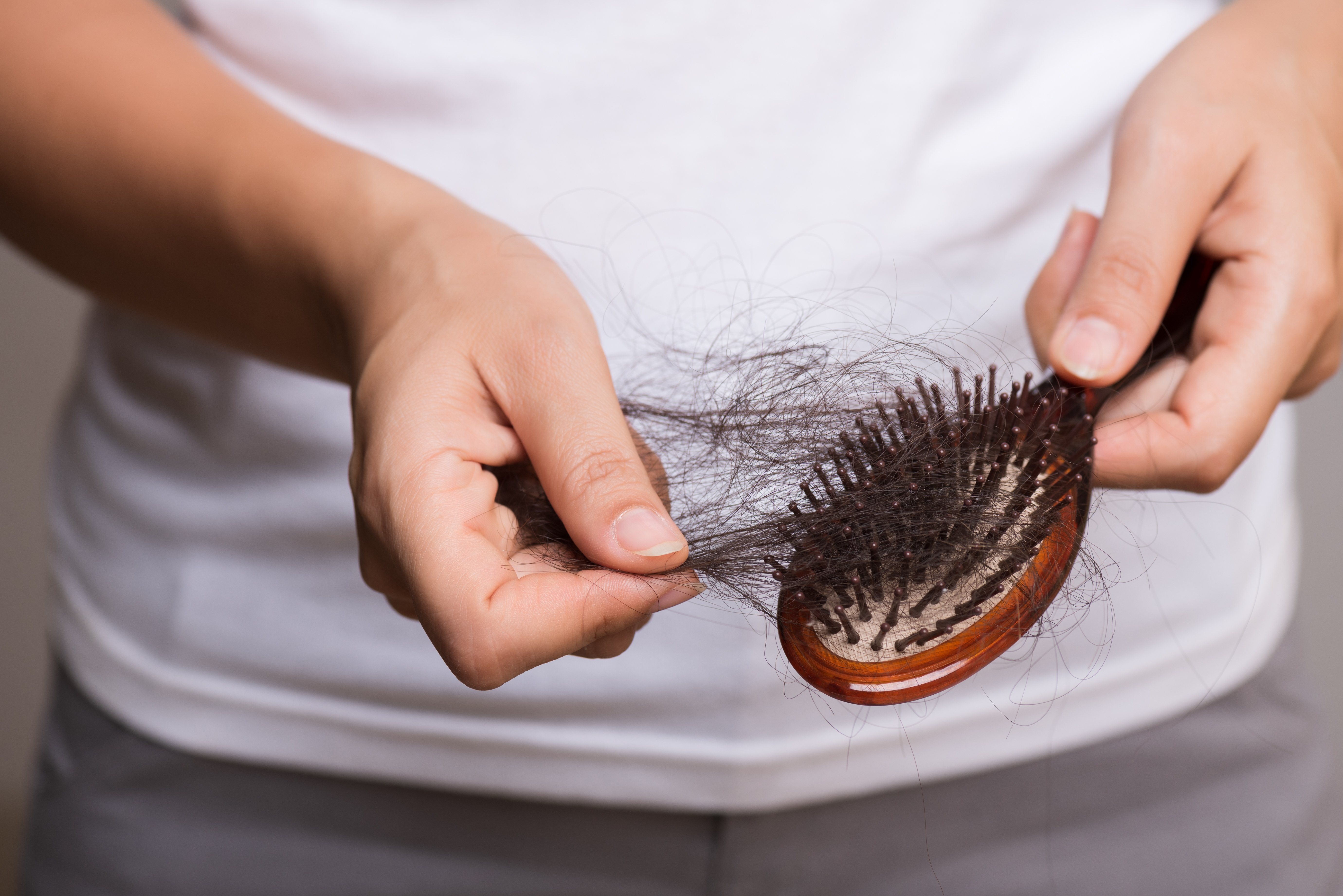 Frau zupft Haare von Bürste | Quelle: Shutterstock